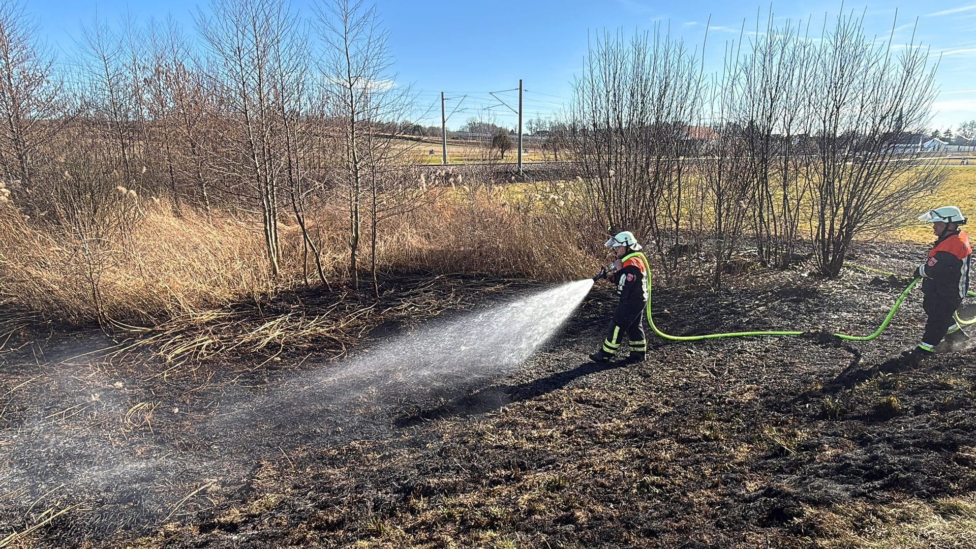 Einsatzkräfte der Feuerwehr löschen einen Brand an einem Bahndamm im Landkreis Pfaffenhofen an der Ilm. Wegen eines Feuers neben den Schienen ist die ICE-Strecke zwischen München und Ingolstadt gesperrt worden