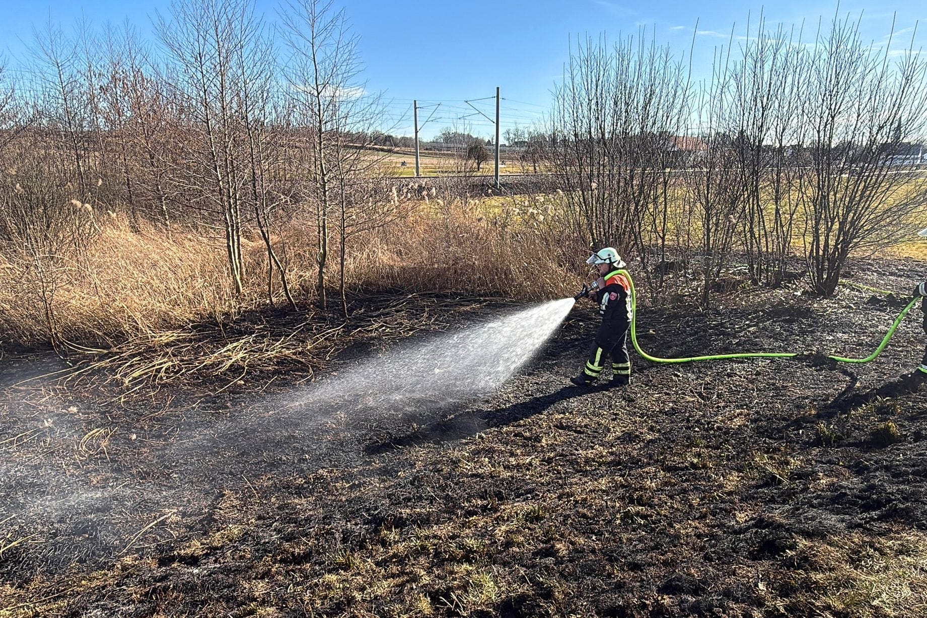 Einsatzkräfte der Feuerwehr löschen einen Brand an einem Bahndamm im Landkreis Pfaffenhofen an der Ilm. Wegen eines Feuers neben den Schienen ist die ICE-Strecke zwischen München und Ingolstadt gesperrt worden