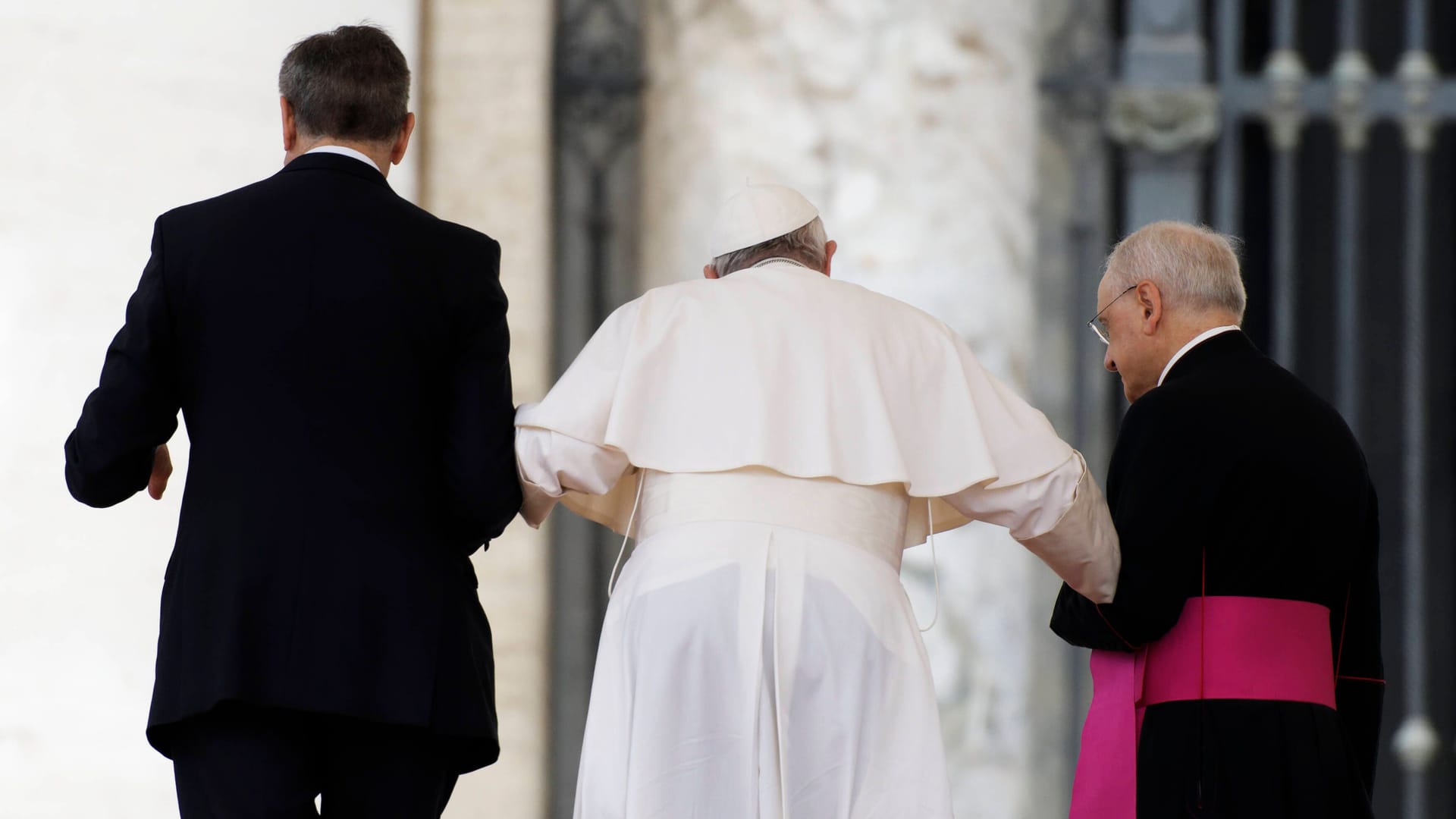 Papst Franziskus wird von zwei Personen gestützt: TikToker versuchen, Beweise für Verschwörungstheorien über seinen Gesundheitszustand zu finden.