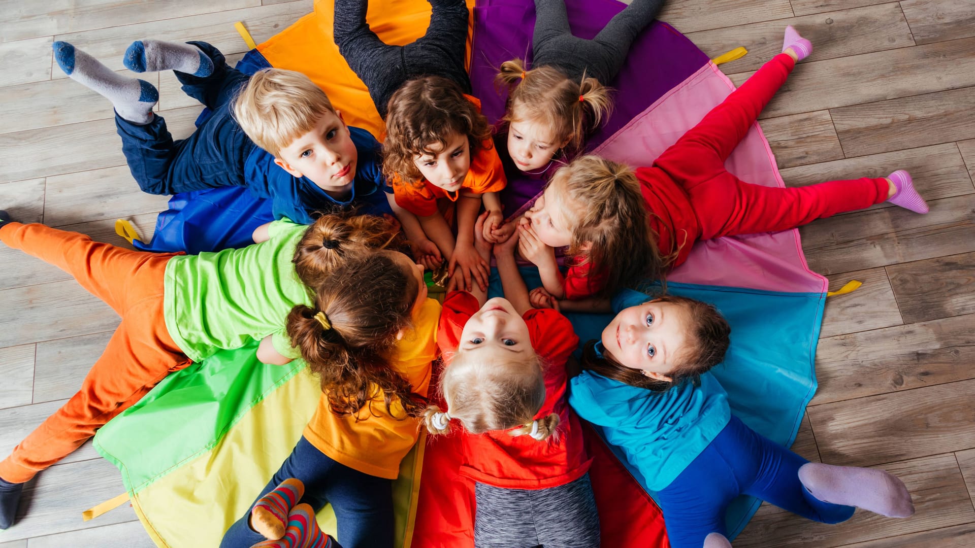 Kinder spielen auf dem Boden (Symbolbild): Die Betreuung in Bremer Kitas soll in Zukunft flexibler gehandhabt werden.