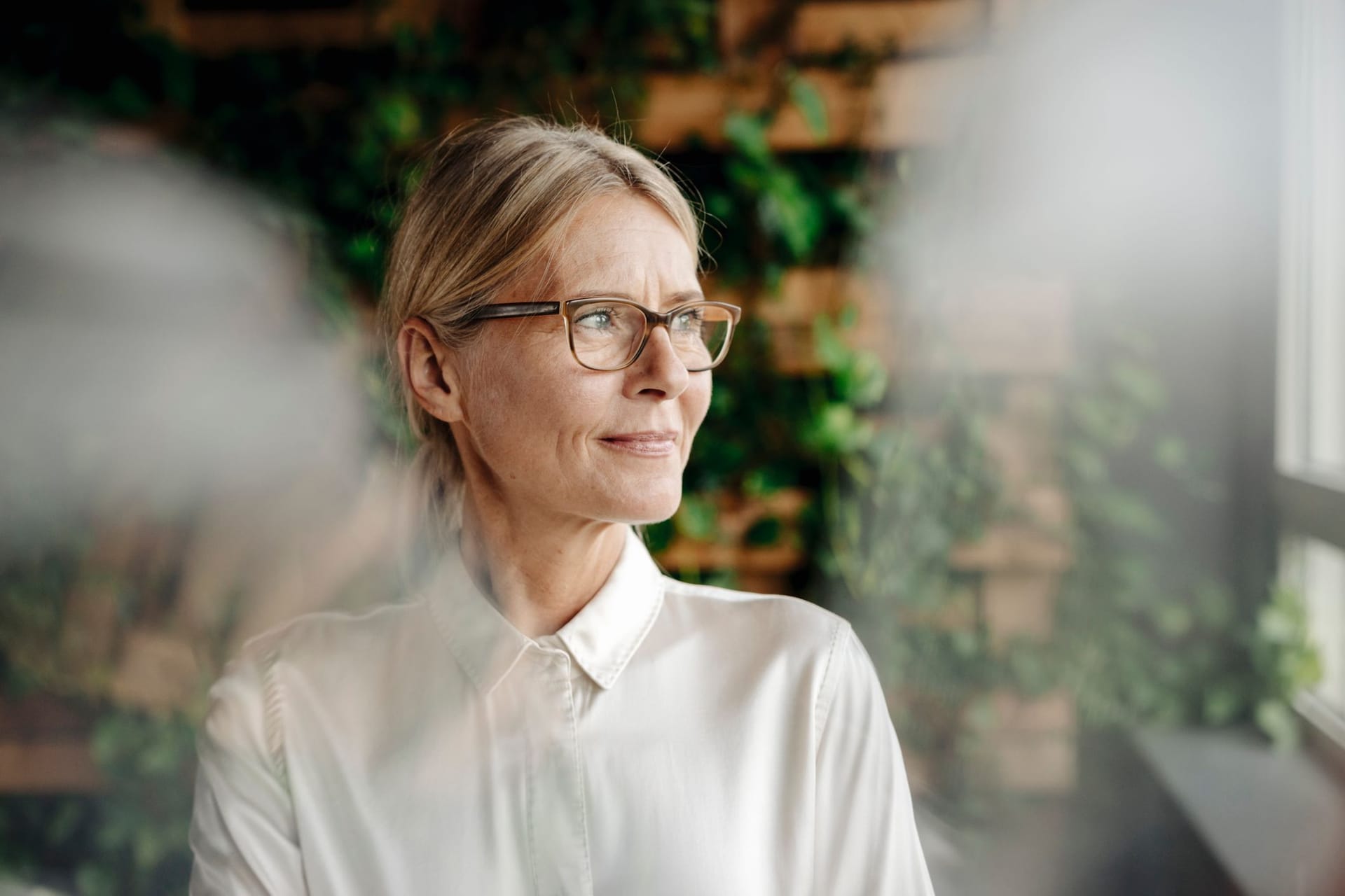 Eine Frau blickt aus dem Fenster: Manche Arbeitnehmer schauen der Rente bereits sehnsüchtig entgegen.