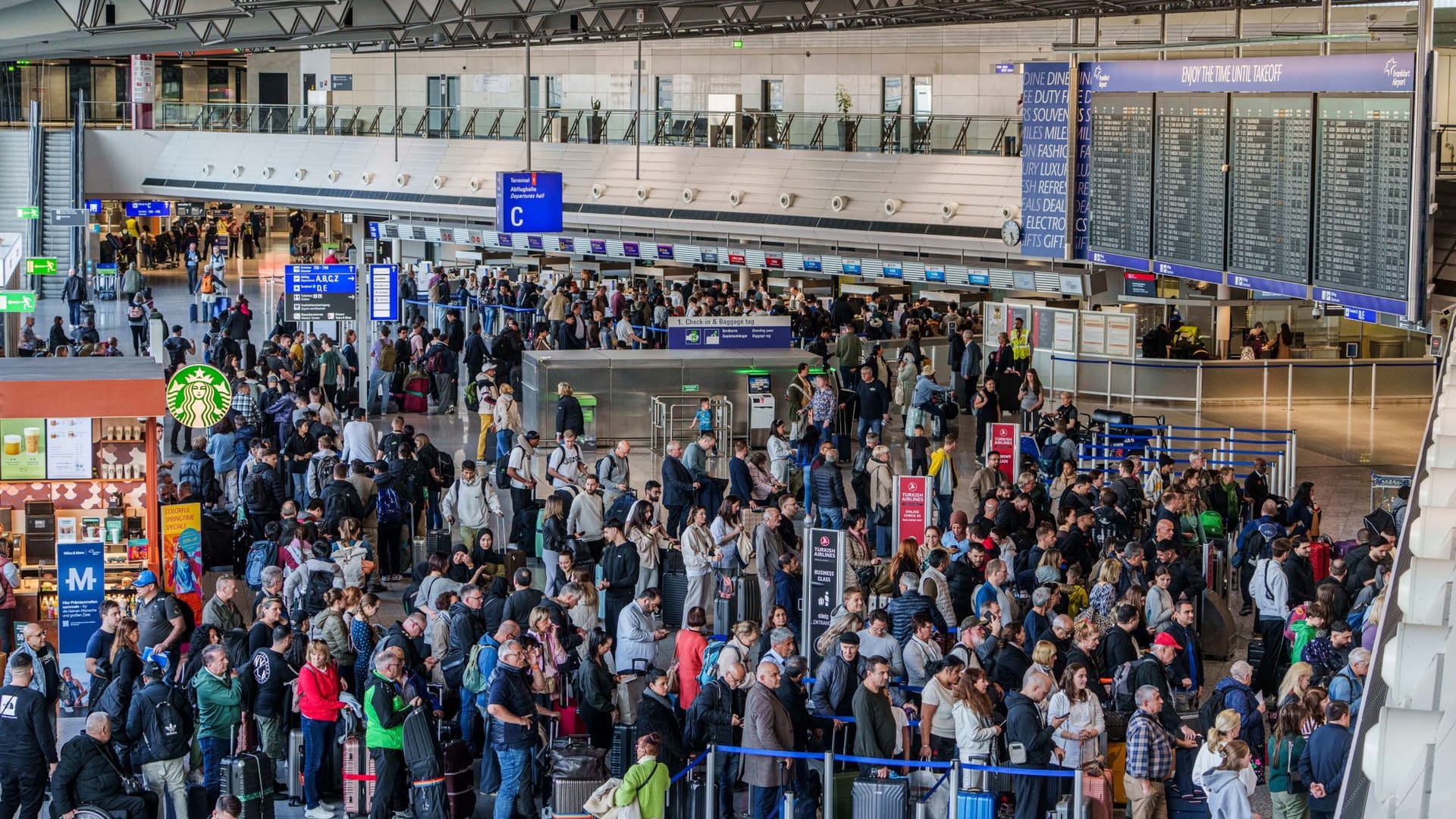 Menschen stehen in der Abflughalle C des Rhein-Main-Airport in langen Schlagen an.