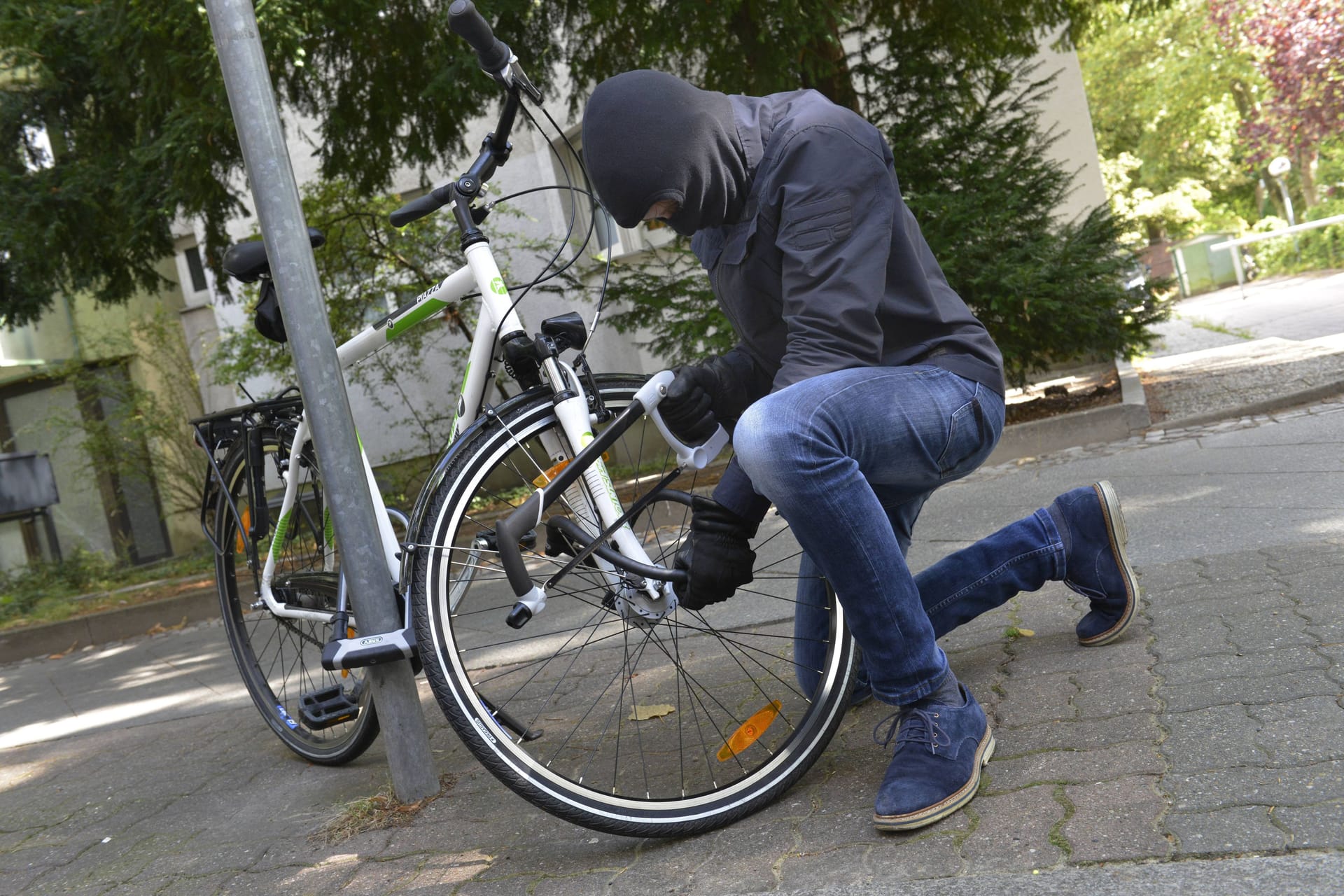 Ein Fahrraddieb macht sich an einem Schloss zu schaffen (Symbolbild): Die geklauten Räder sollten wohl ins Ausland gebracht werden.