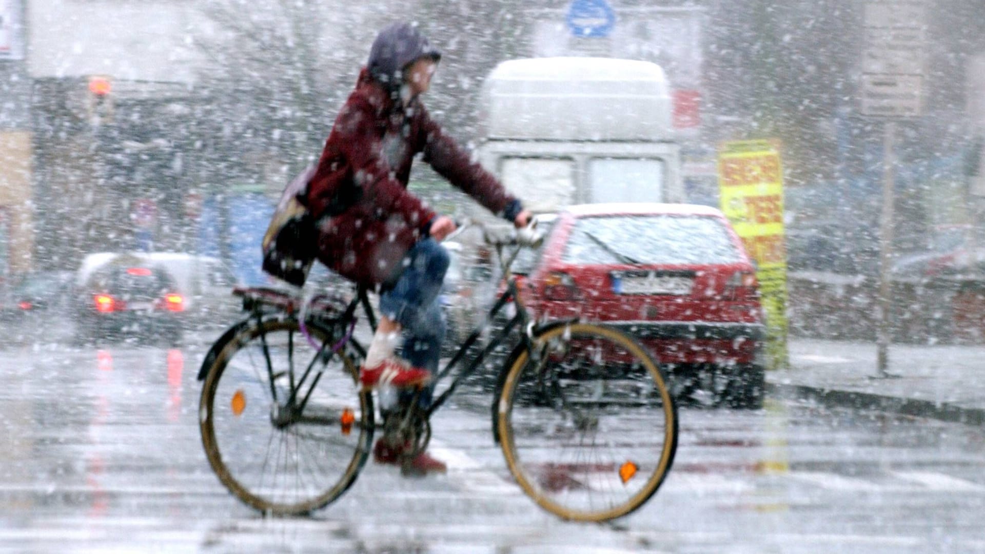 Eine Radlerin fährt durch einen Graupelschauer (Archivbild): In den nächsten Tagen hat das Wetter von Sonne bis Frost fast alles zu bieten.