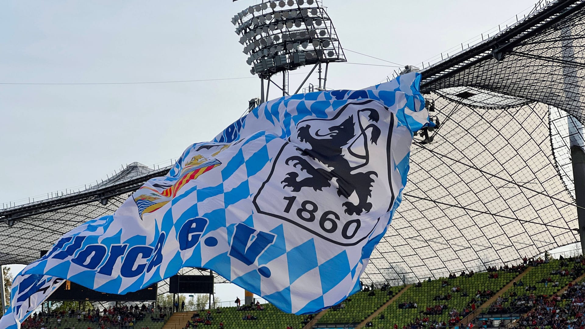 Fans von 1860 München schwenken eine Fahne im Olympiastadion (Archivbild): Dieses war zuletzt immer wieder als mögliche Ausweichspielstätte der "Löwen" in Betracht gezogen worden.