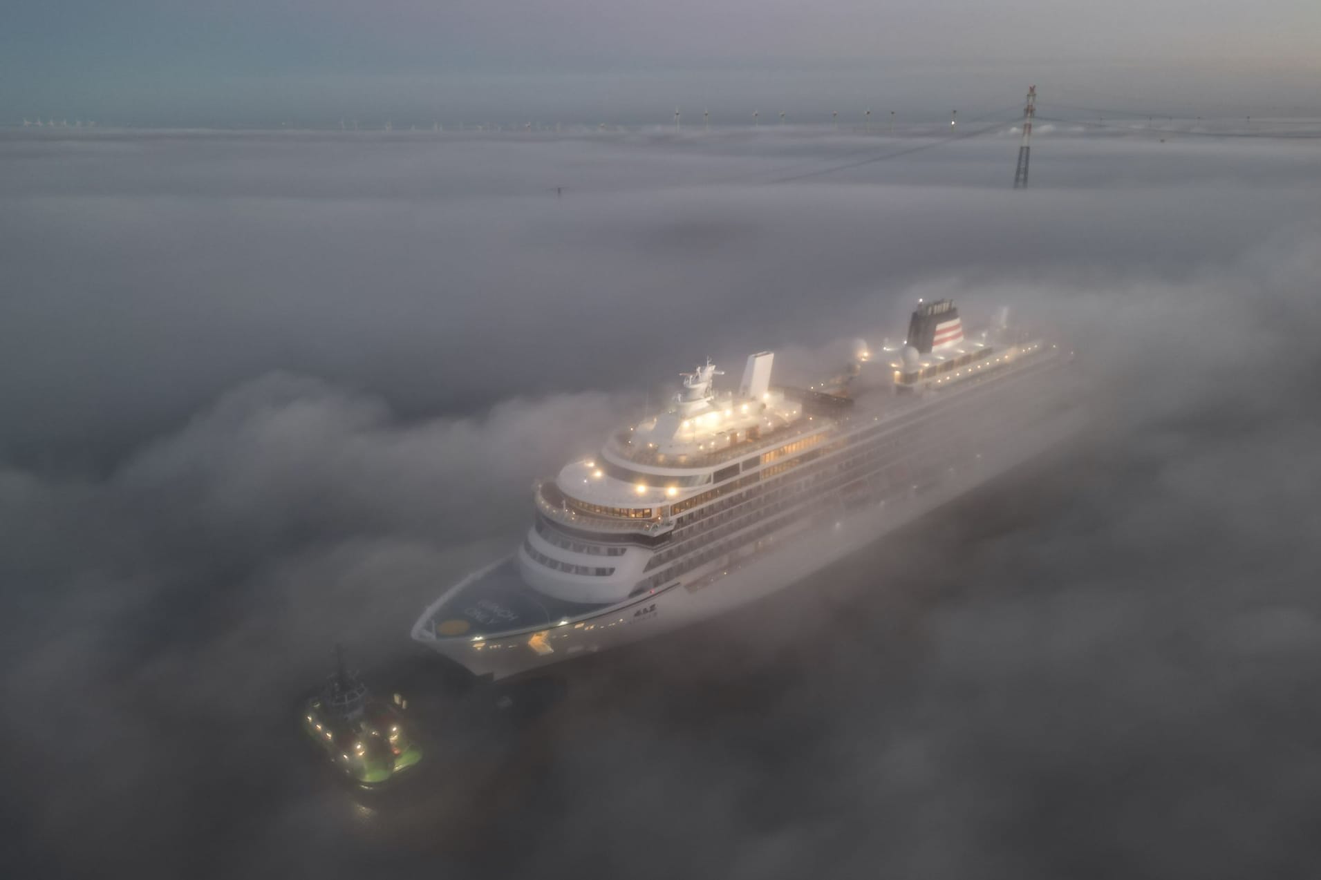 Im dichten Nebel wird das Luxus-Kreuzfahrtschiff überführt. Das Spektakel zieht viele Schaulustige an.