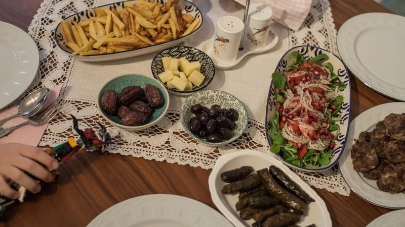 Kinder und Eltern nehmen während des heiligen Fastenmonats Ramadan ein gemeinsames Iftar-(Fastenbrechen-)Essen in ihrer Wohnung ein. Tagsüber nehmen Gläubige im Ramadan nichts zu sich, erst nach Sonnenuntergang essen und trinken sie beim Fastenbrechen - Iftar.