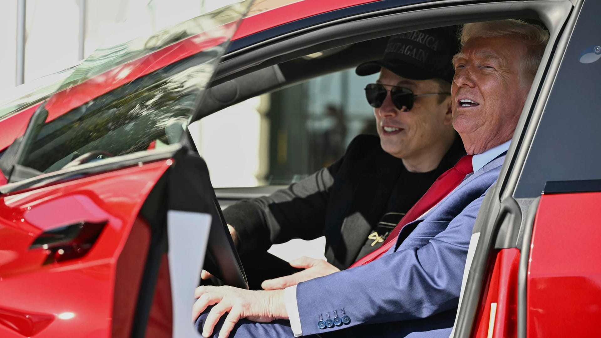 Donald Trump (r.) und Elon Musk sitzen in einem neuen Tesla. Trotz der PR-Aktion sinken die Verkaufszahlen den Elektroautobauers.