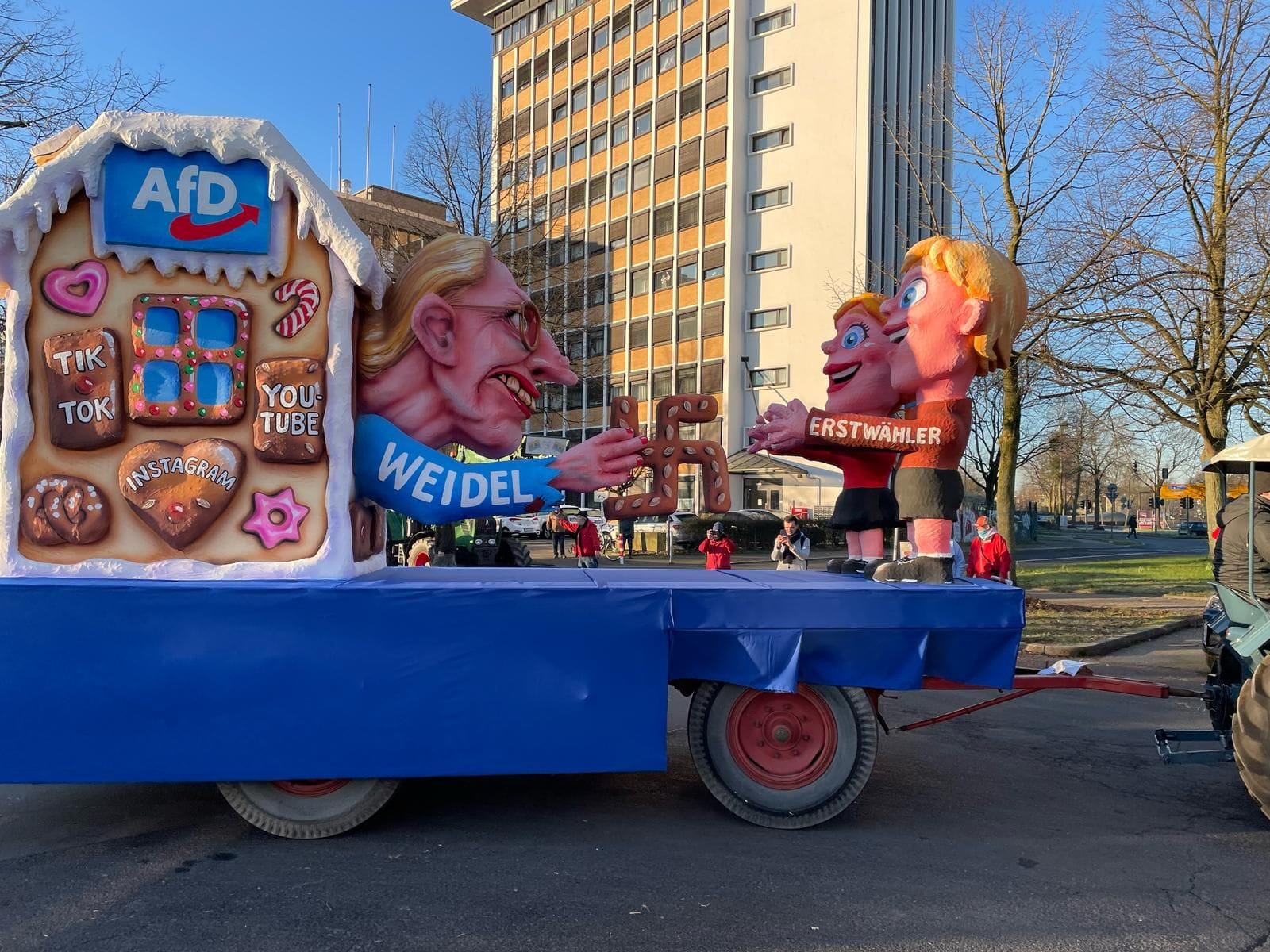 Alice Weidel verführt als "Hexe" Erstwähler: Die AfD-Chefin ist als Hexe aus "Hänsel und Gretel" zu sehen, wie sie aus ihrem Haus Lebkuchen in Hakenkreuz-Form verteilt. Tilly hat dabei mit Warzen im Gesicht von Weidel nicht gespart. Das Haus schmücken außerdem Lebkuchen mit den Aufschriften: "TikTok", "Instagram" und "Youtube". Auf der anderen Seite stehen die "Erstwähler", die bereitwillig in Weidels Arme laufen.