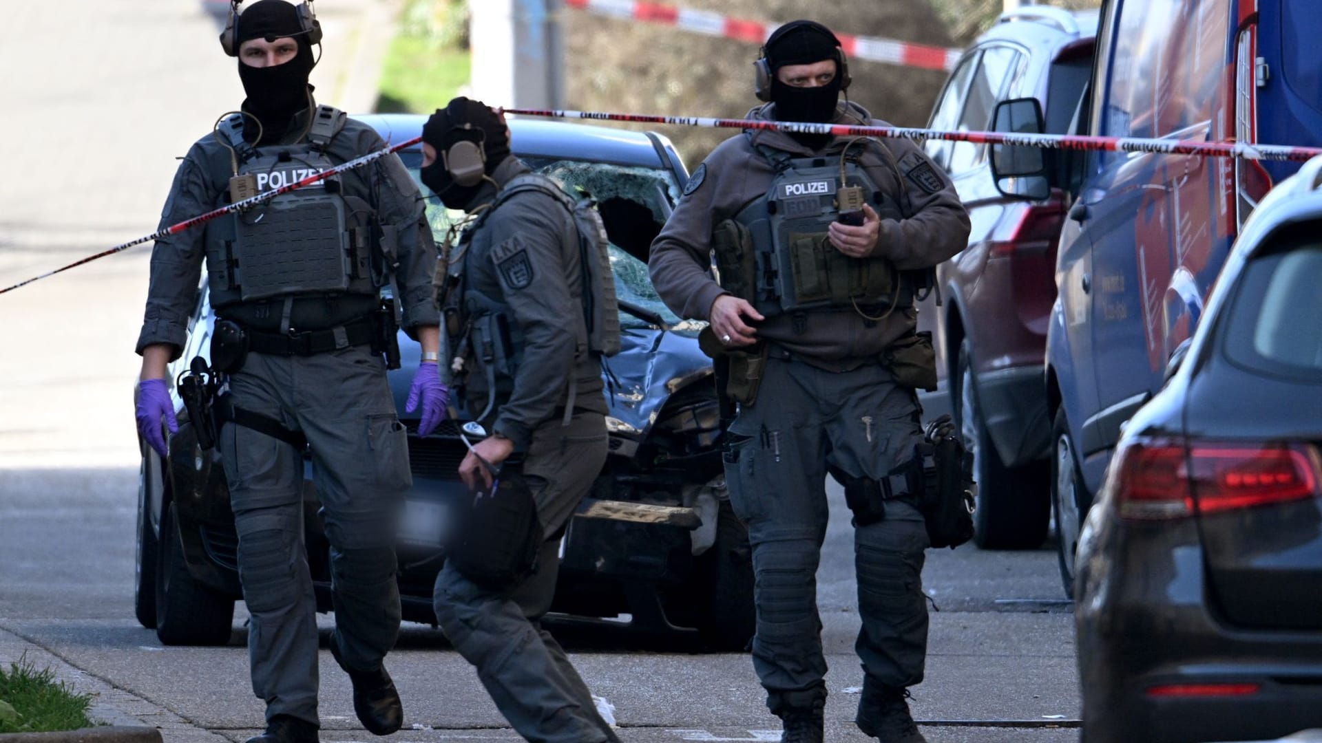 Beamte des Entschärfungsdienstes der Polizei sind an einem beschädigten Fahrzeug an einer Zufahrt zur Rheinbrücke im Einsatz.