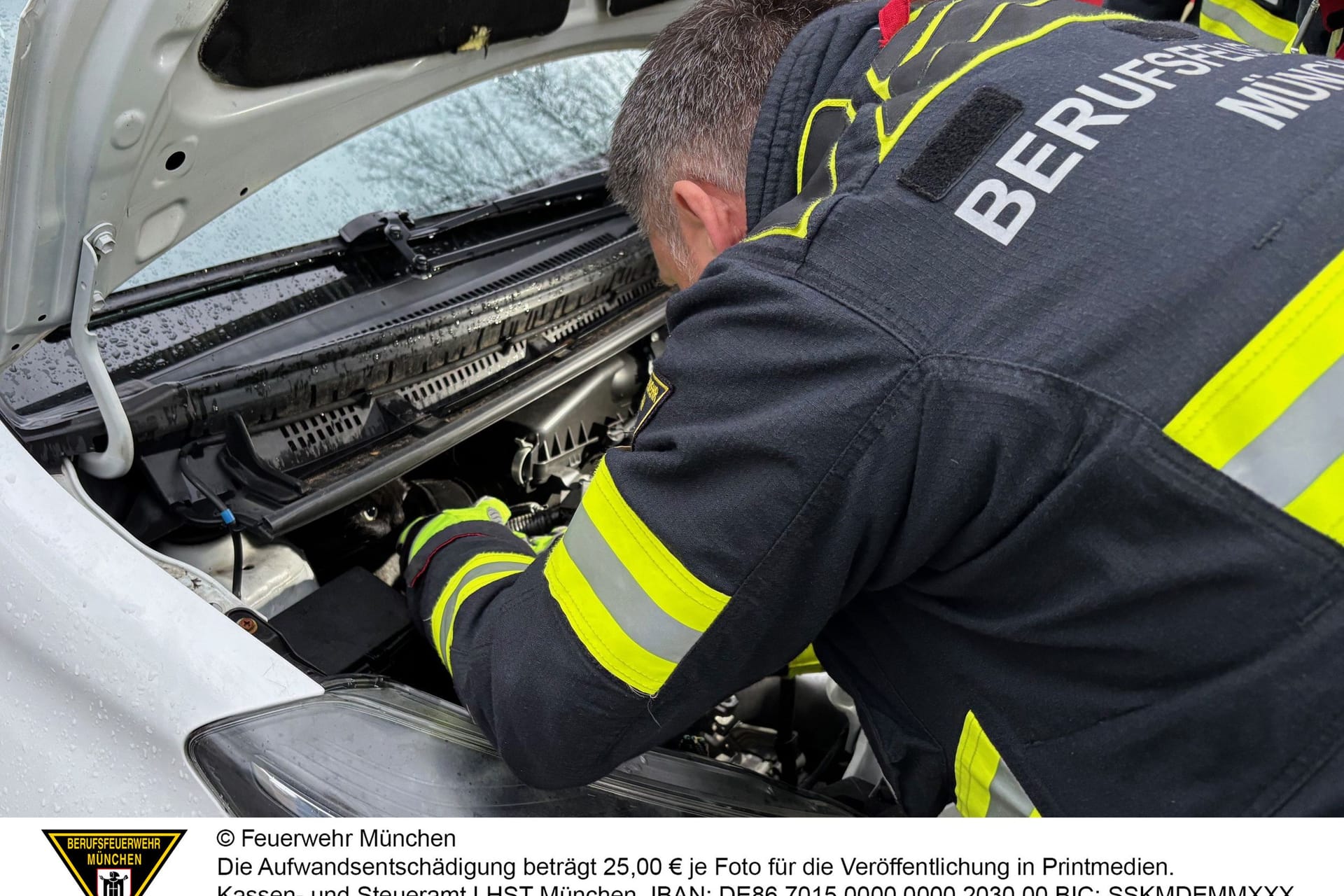 Ein Feuerwehrmann befreite die eingeklemmte Katze aus dem Motorraum eines Autos.