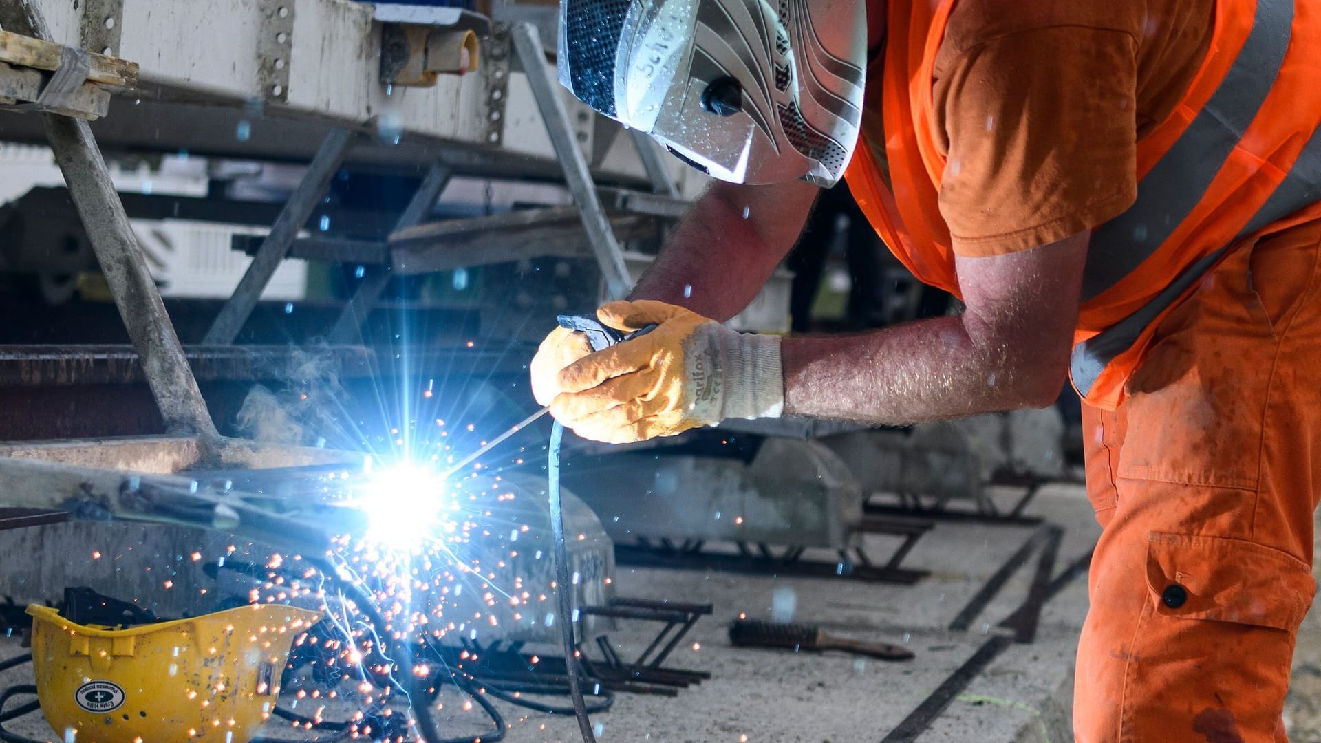 Bauarbeiter bei Schweißarbeiten an einer Baumaschine