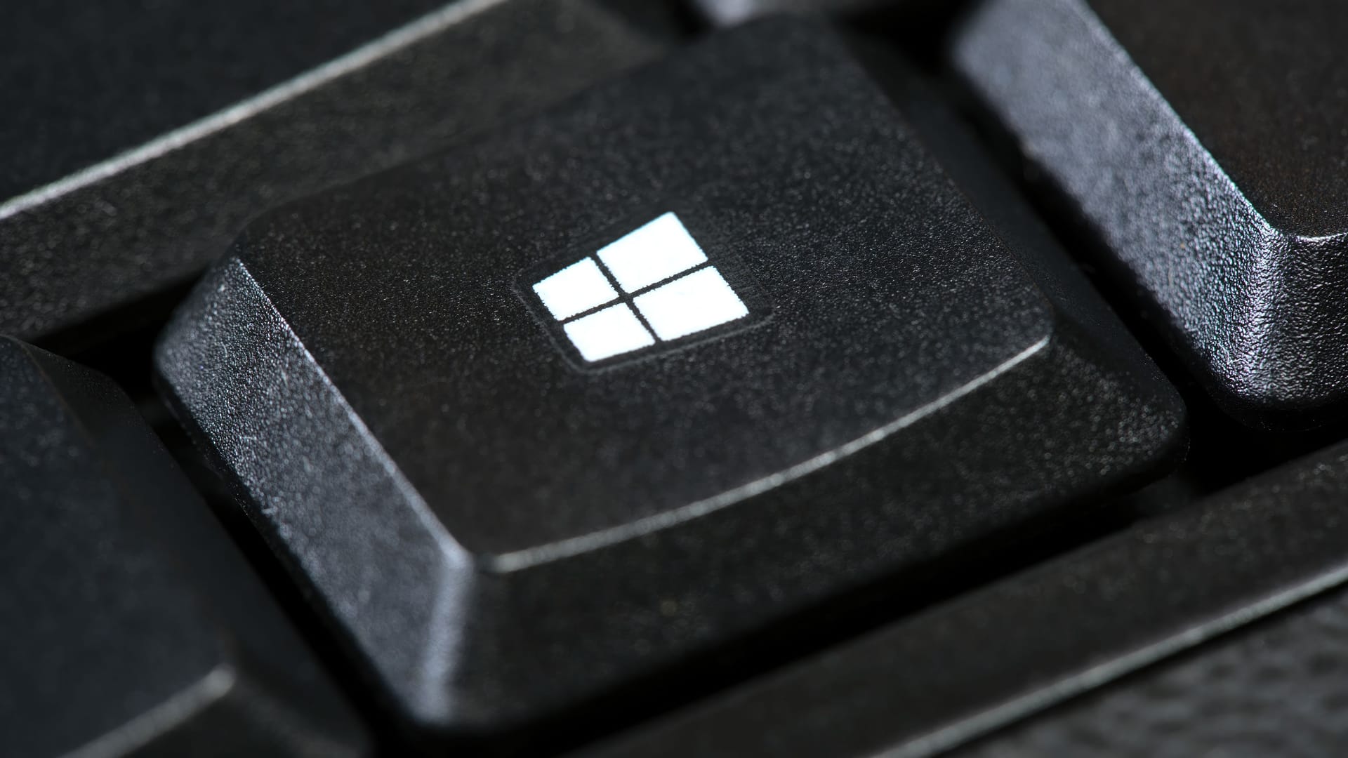 Microsoft Windows OS logo, operating system key on a simple black desktop PC computer keyboard, macro, extreme closeup. OS button brand detail. Operating systems concept