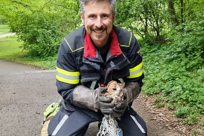 Ein Feuerwehrmann und der gerettete Jungvogel.