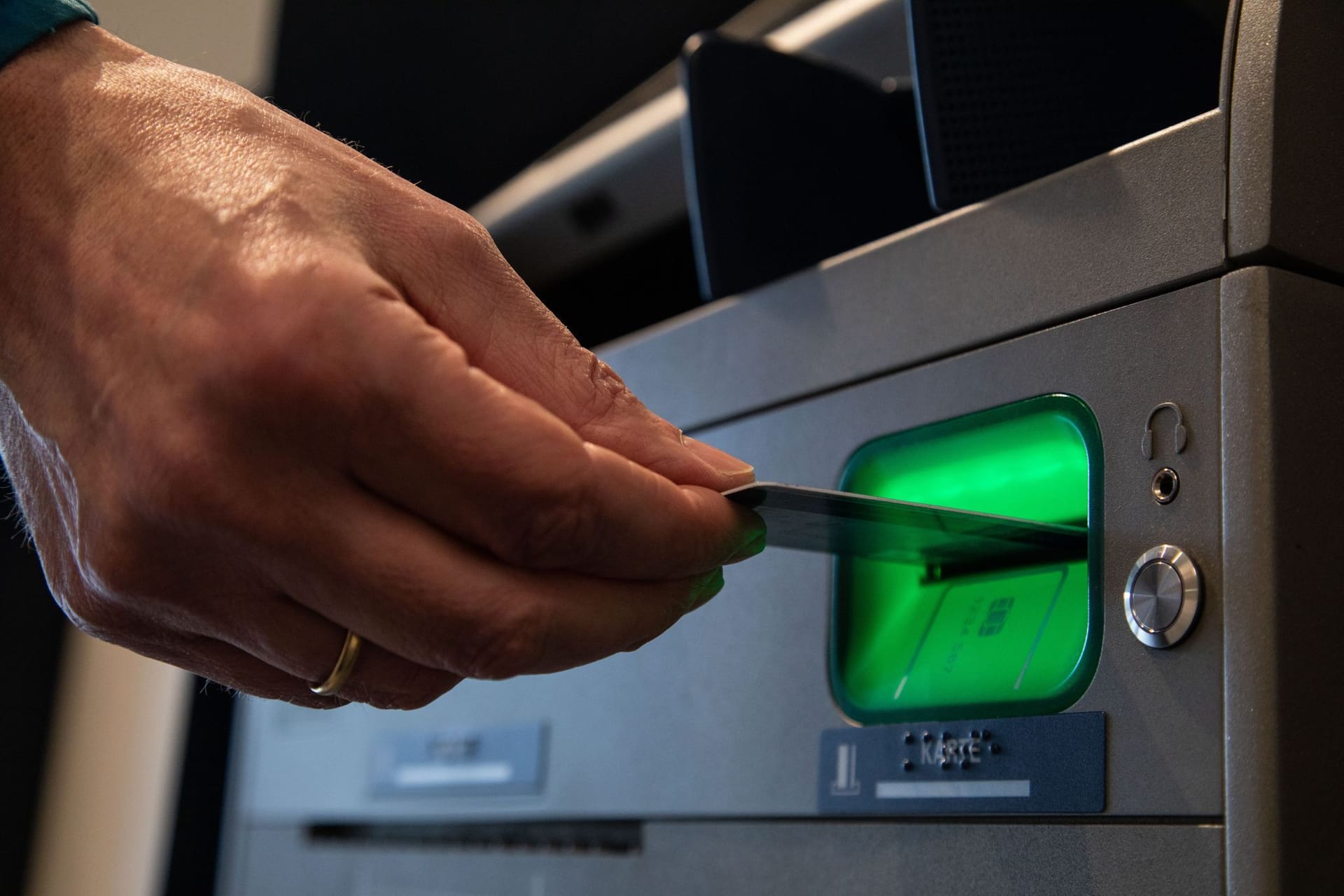 Mann gibt Karte in einen Bankautomaten