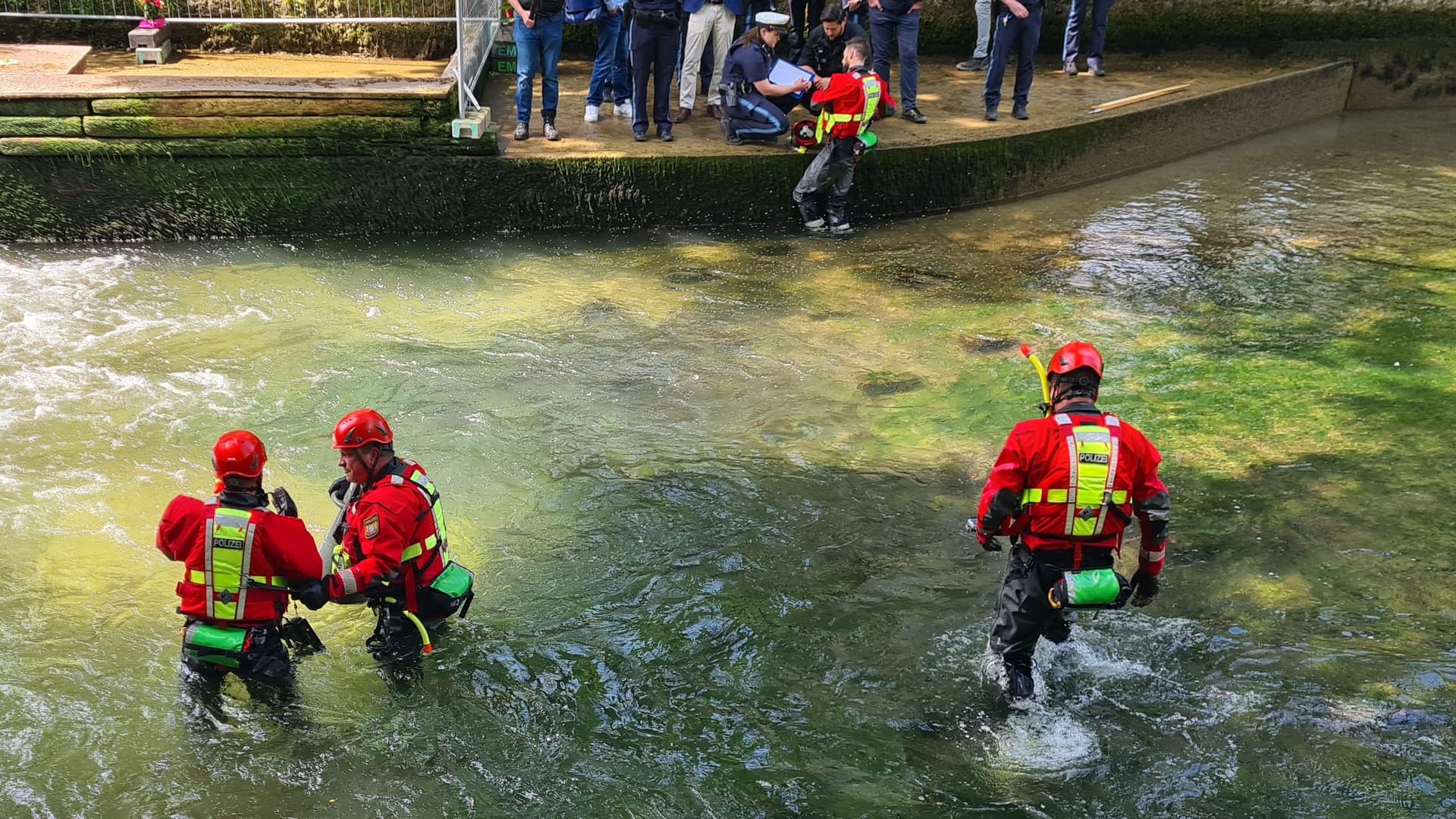 Einer der Taucher macht Meldung bei seinen am Rande stehenden Kollegen: Außer mehrerer kleinerer Gegenstände wurde bei dem Einsatz am Mittwoch nichts gefunden.
