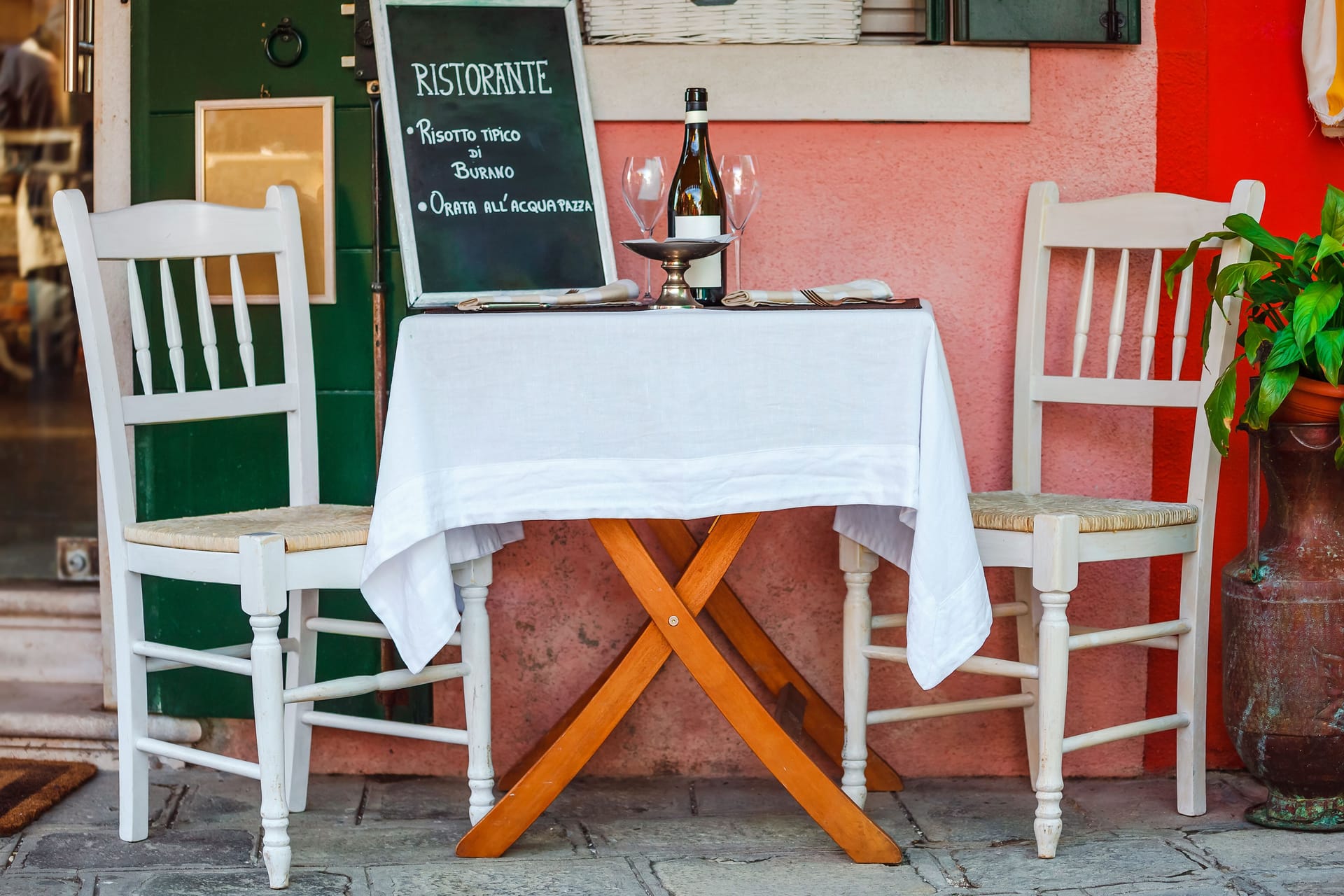 Ein italienisches Ristorante: Der Tisch ist fein gedeckt, mit weißer Tischdecke und Weingläsern.