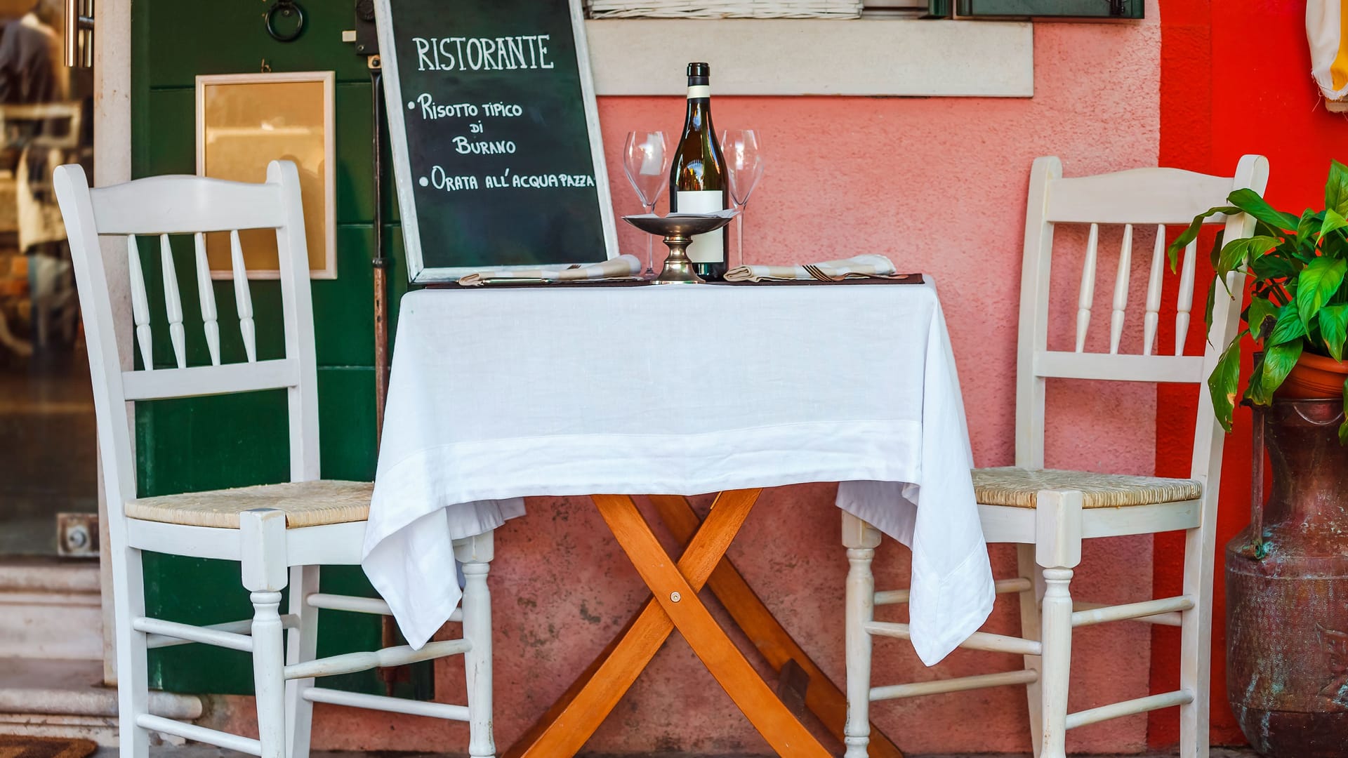Ein italienisches Ristorante: Der Tisch ist fein gedeckt, mit weißer Tischdecke und Weingläsern.