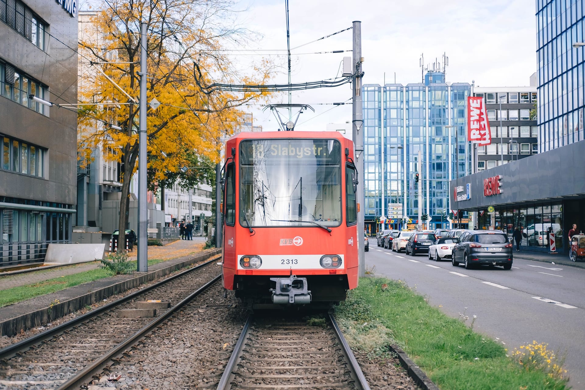 In Cologne, streetcar line 18 towards Slabystrasse is parked in front of Barbarossaplatz, waiting.