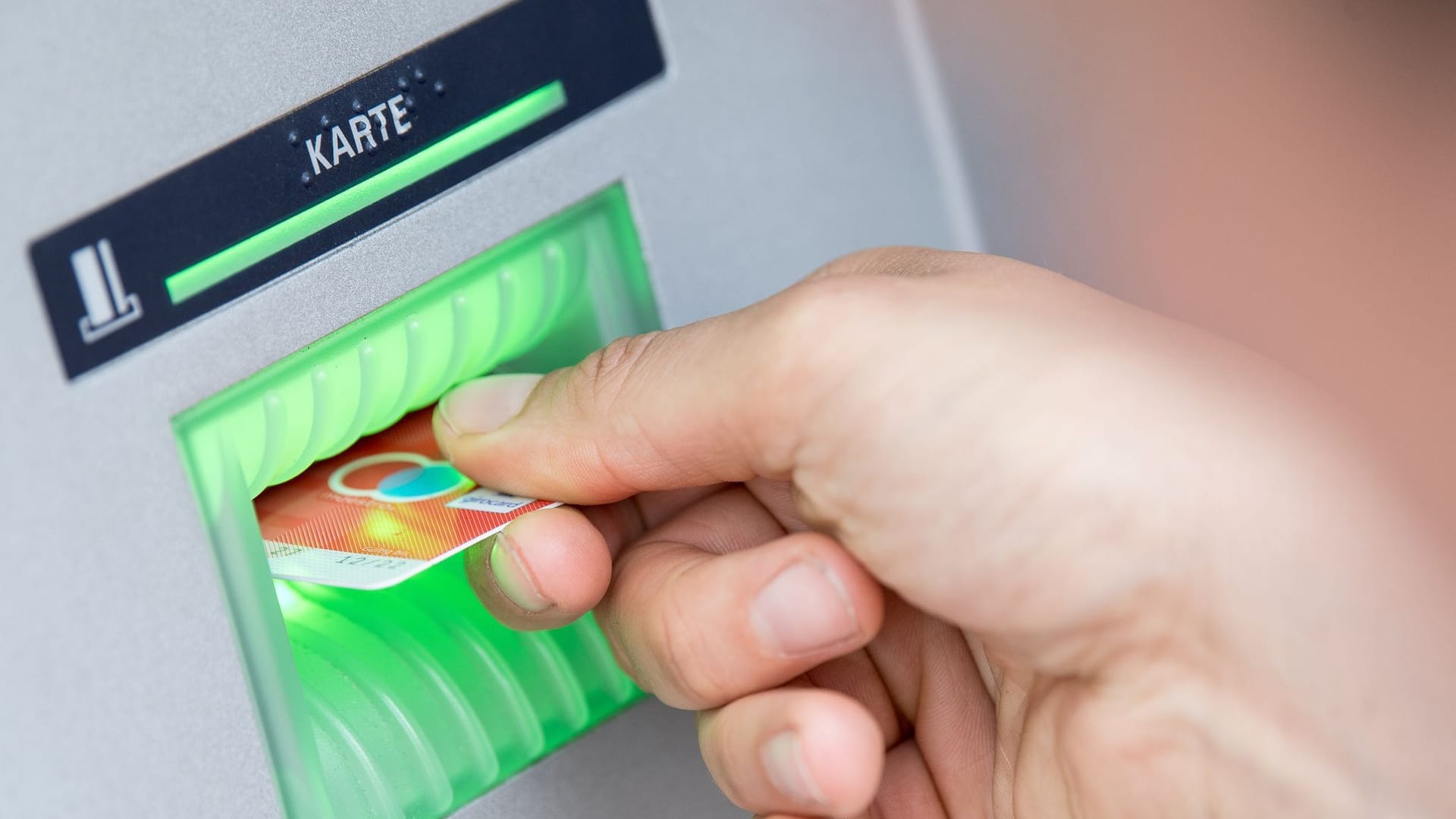 Ein Mann hebt am Automaten Geld ab Ein Mann hebt am Automaten Geld ab