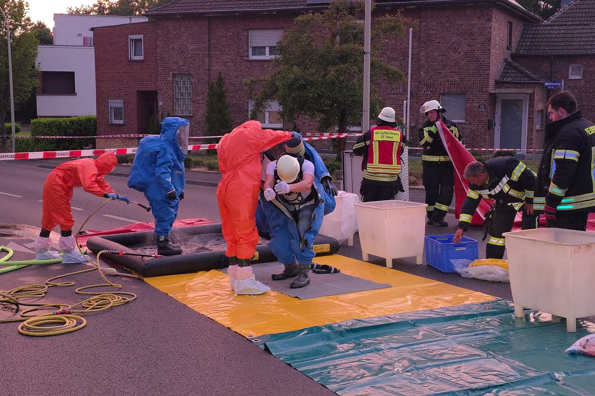 Einsatzkräfte werden am Mühlenweg in Übach-Palenberg mit Schutzanzügen ausgerüstet: Offenbar wurden mehrere Polizisten zuvor durch reizende Gase verletzt.