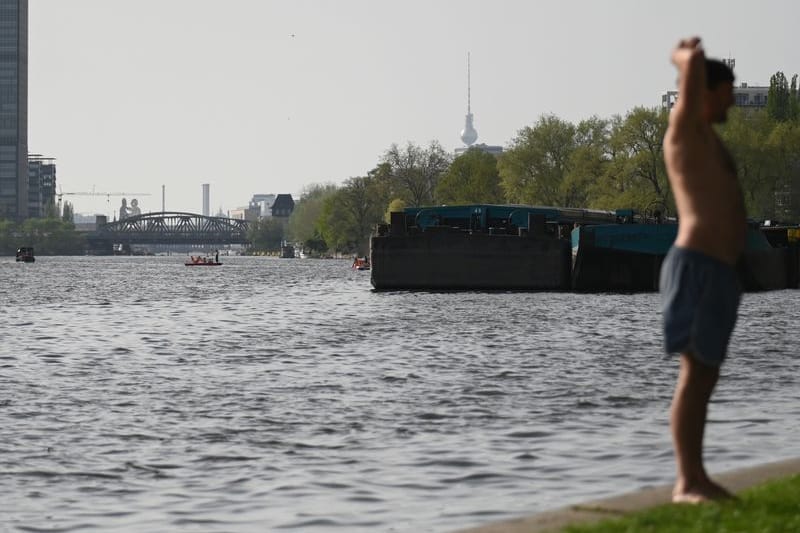 Ein Mann steht in Badehose an der Spree auf Berlin-Stralau und genießt die Sonne. Im Hintergrund ist der Fernsehturm und die Elsenbrücke. (zu dpa: «Bezirk Mitte möchte Baden in Spree gerne wieder ermöglichen»)