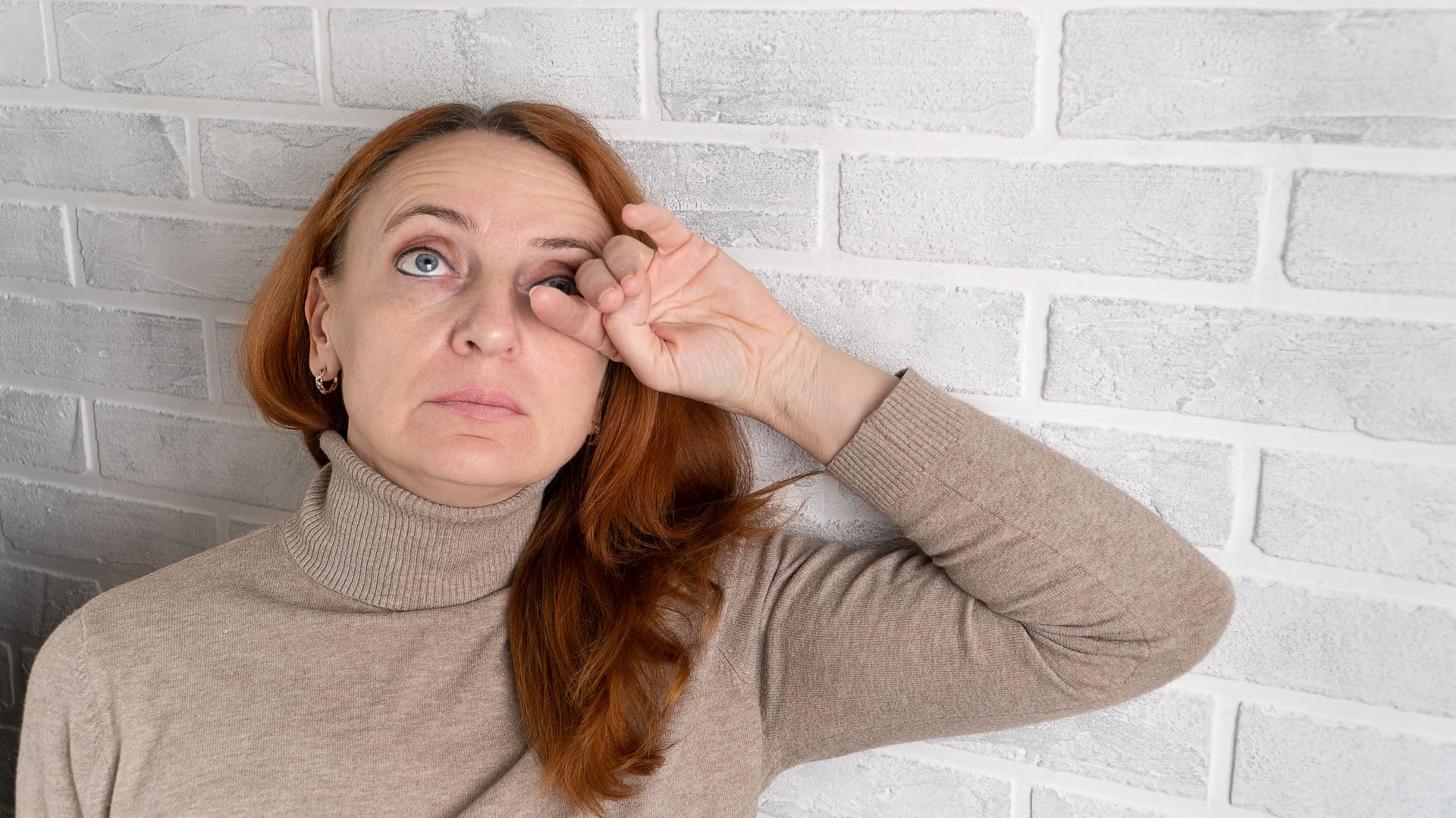 Frau fasst sich an ihr linkes Auge: Ein Gerstenkorn entsteht durch Bakterien. Frau fasst sich an ihr linkes Auge: Ein Gerstenkorn entsteht durch Bakterien.
