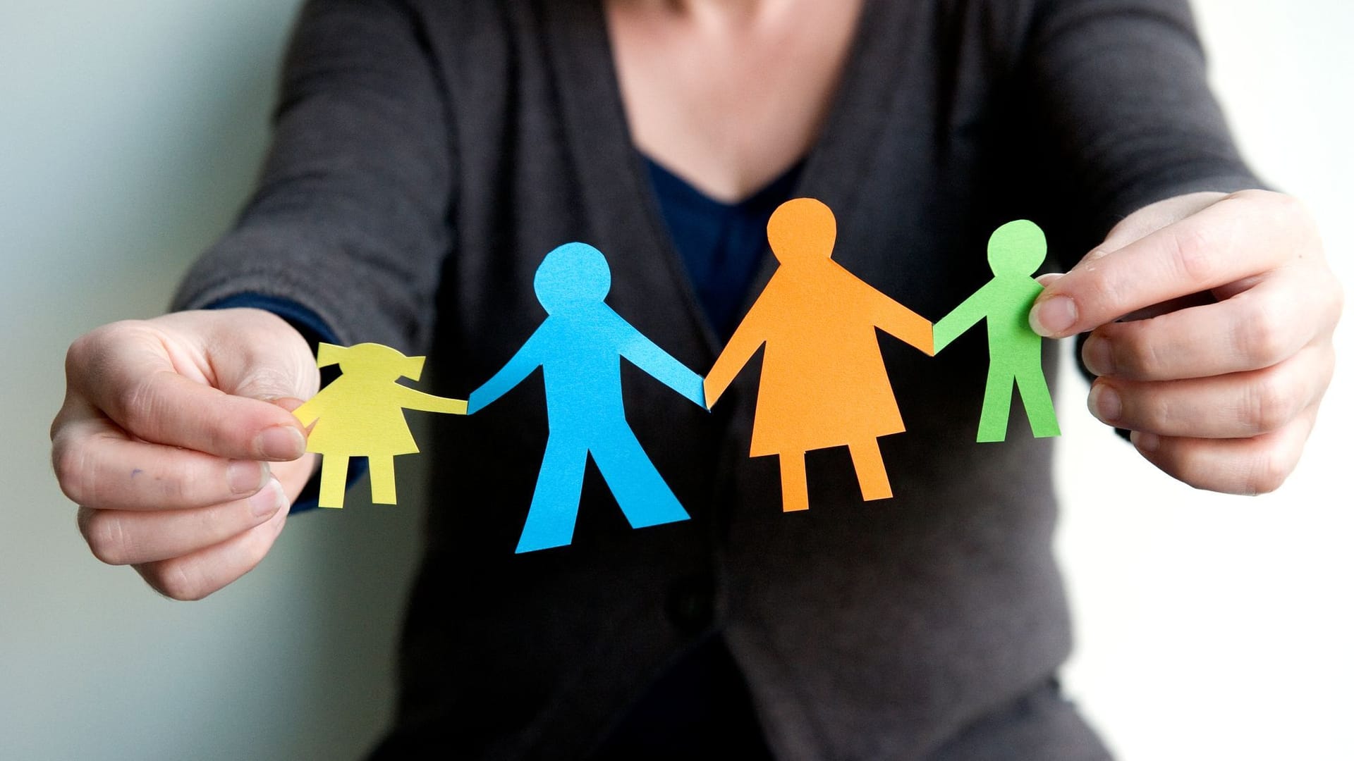 Eine Frau hält eine Familie aus buntem Papier Eine Frau hält eine Familie aus buntem Papier