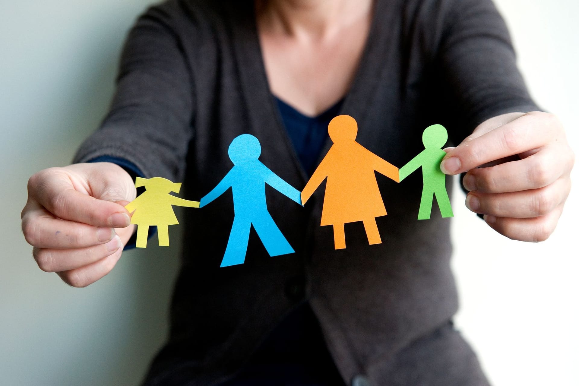 Eine Frau hält eine Familie aus buntem Papier Eine Frau hält eine Familie aus buntem Papier