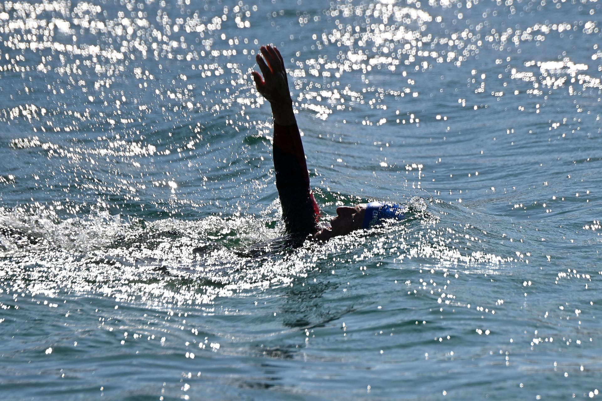 Ein Mann schwimmt in einem See (Symbolbild): In Niedersachsen wird die Wasserqualität der Badeseen kontrolliert.