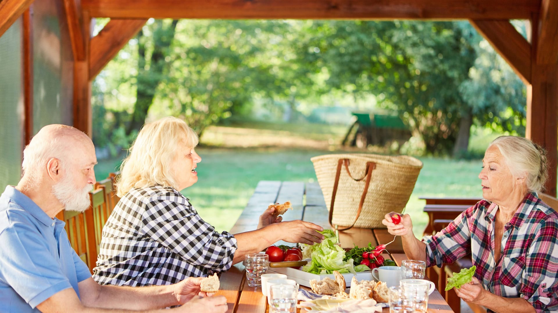 Urlauber genießen ein Essen auf der Veranda: Wer einen längeren Ferienhausurlaub plant, sollte besonders auf die Ausstattung achten.