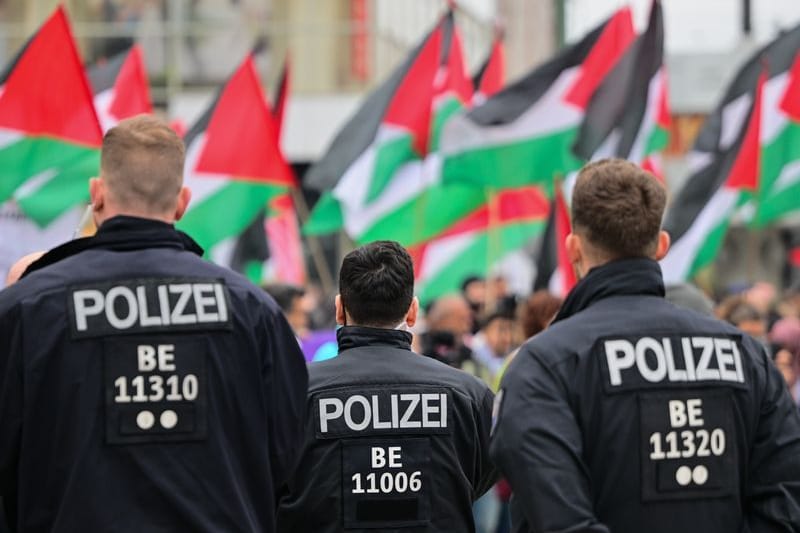 Palästinensische Fahnen werden während einer propalästinensischen Demonstration hinter Polizeibeamten geschwungen. (zu dpa: «Demo zum Gedenktag Nakba muss doch am Südstern bleiben»)
