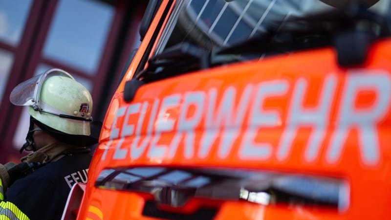 Eine Einsatzkraft der Feuerwehr steht neben einem Einsatzfahrzeug der Feuerwehr. (Symbolbild) Eine Einsatzkraft der Feuerwehr steht neben einem Einsatzfahrzeug der Feuerwehr. (Symbolbild)