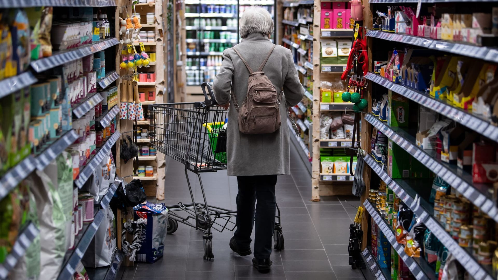 Eine Frau geht mit Einkaufswagen durch einen Supermarkt Eine Frau geht mit Einkaufswagen durch einen Supermarkt