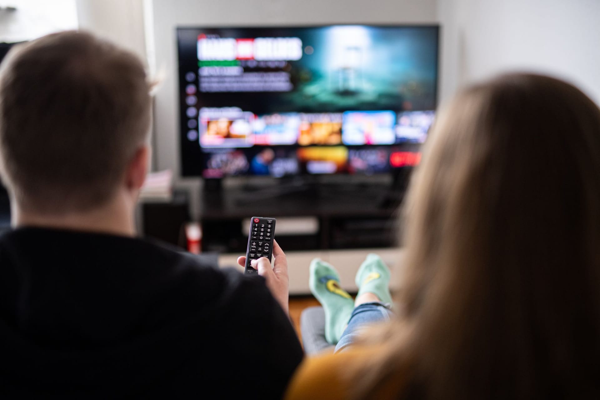 Paar sitzt vor einem Fernseher mit Streamingdiensten