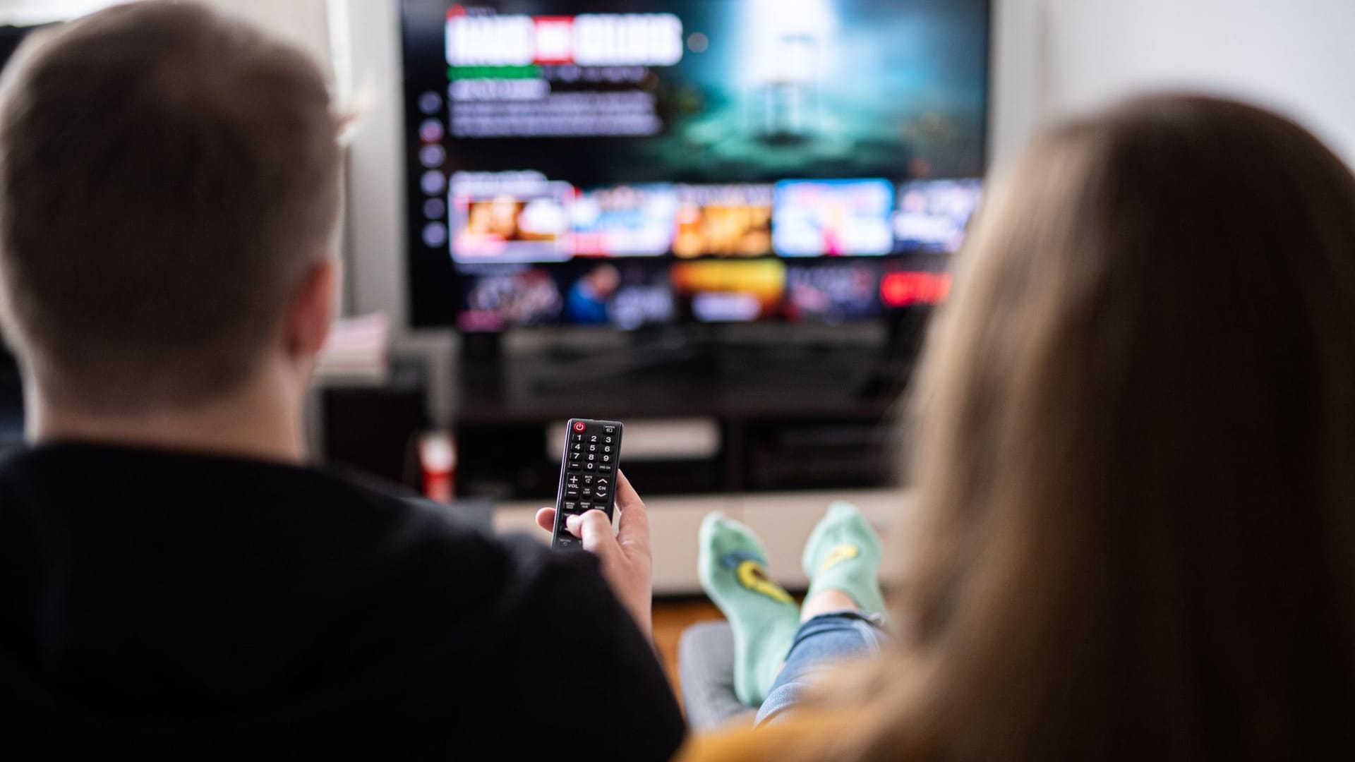 Paar sitzt vor einem Fernseher mit Streamingdiensten Paar sitzt vor einem Fernseher mit Streamingdiensten