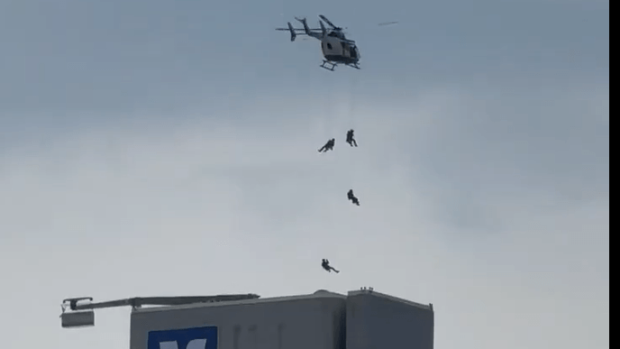 Ein Video in sozialen Medien zeigt die spektakuläre Aktion. Mehrere Beamte seilen sich aus einem Hubschrauber über dem Westend Tower ab.