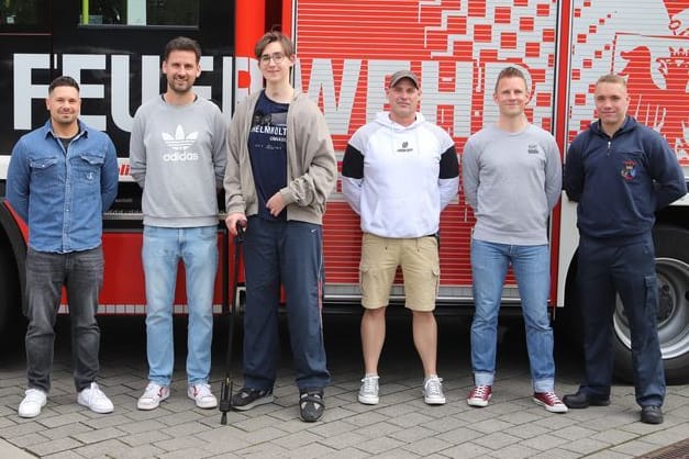 Keanu Fredriksson (3.vl) steht mit Einsatzkräften der Feuerwehr, die bei seinem Unfall im Einsatz waren, vor einem Löschfahrzeug: Rund anderthalb Jahre nach einem dramatischen Unfall hat ein damals 17-jähriger Schüler aus Essen seinen Lebensrettern bei der Feuerwehr in Essen gedankt.
