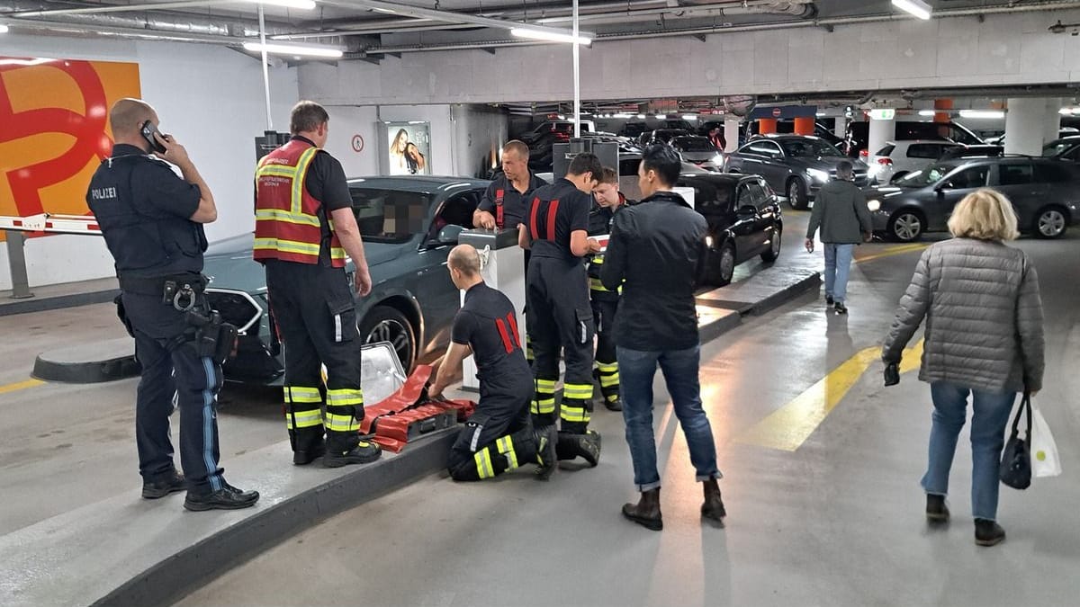 Einsatzkräfte der Feuerwehr mit der demontierten Schranke, während Autofahrer auf ihre Ausfahrt warten.