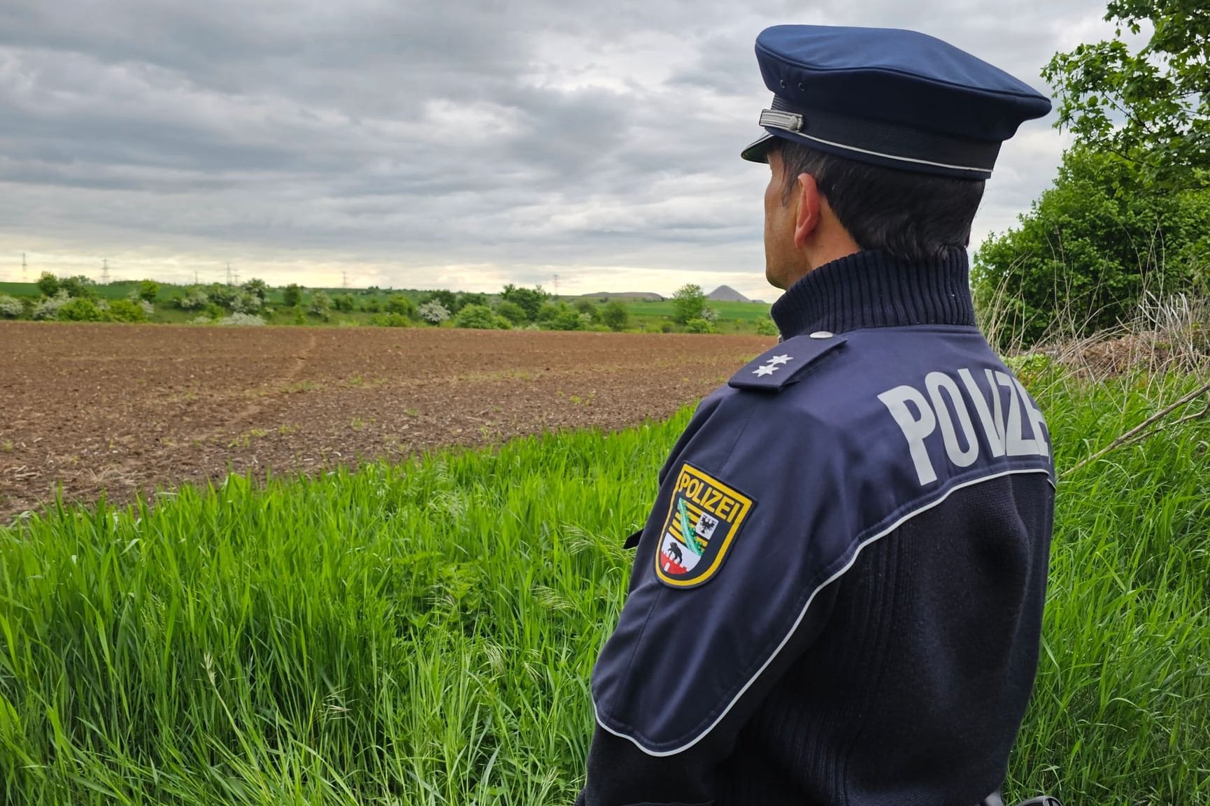 Ein Polizist der Polizeiinspektion Halle steht am Fundort an einem Feld am Rande von Benndorf: Ob es sich tatsächlich um die Leiche von Sandra K. handelt, wird noch untersucht.