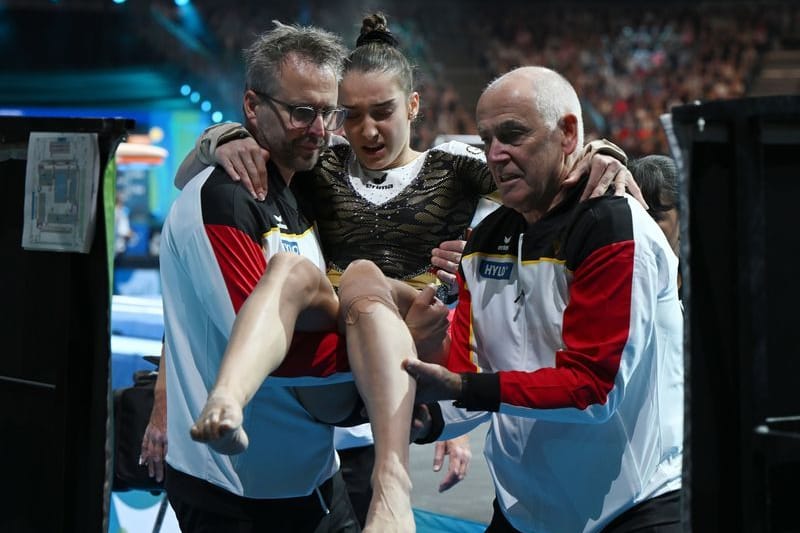 Helen Kevric (M.) wird nach ihrer Übung am Sprung verletzt zur Seite getragen: Die Schwere der Verletzung ist bisher nicht bekannt.