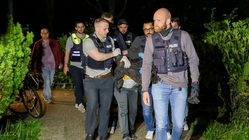 Einsatzkräfte der Polizei führen einen Tatverdächtigen nach seiner Festnahme ab.