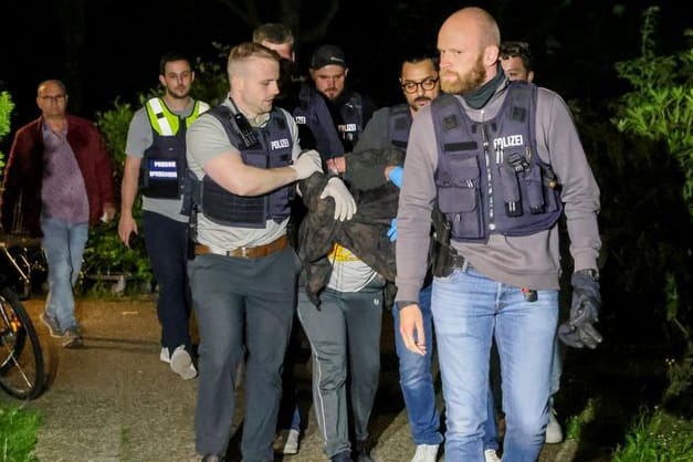 Einsatzkräfte der Polizei führen einen Tatverdächtigen nach seiner Festnahme ab.