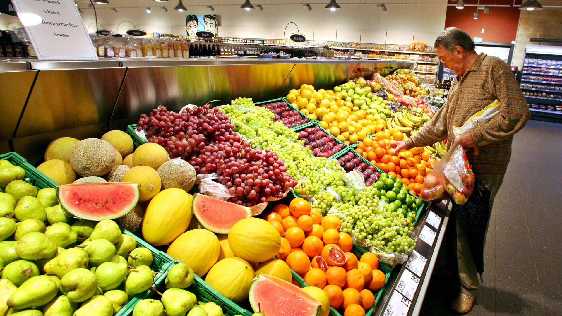 Mann vor Obstauslage in einem Supermarkt (Symbolbild): Einige Märkte öffnen am Feiertag ihre Türen.