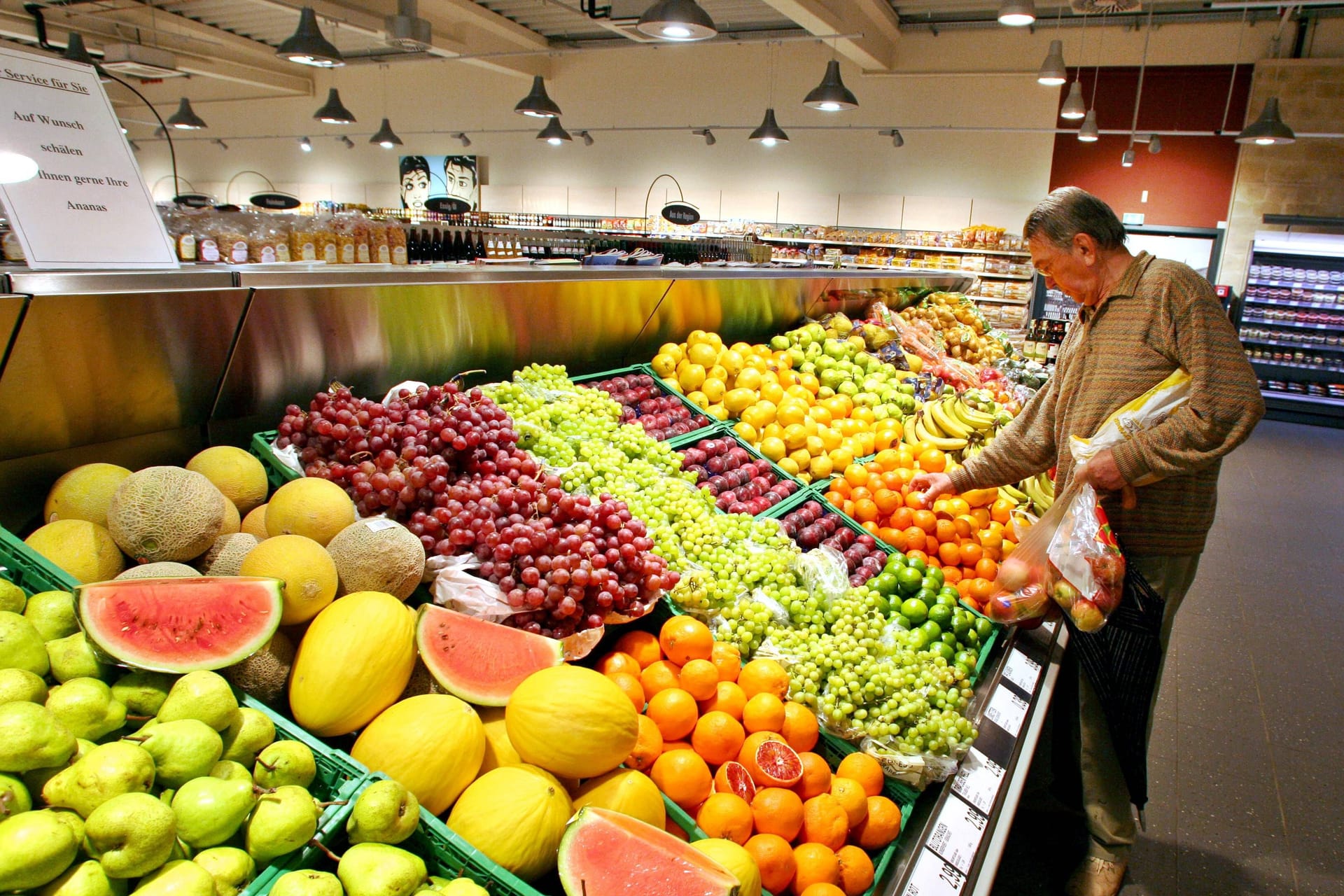 Mann vor Obstauslage in einem Supermarkt (Symbolbild): Einige Märkte öffnen am Feiertag ihre Türen. Mann vor Obstauslage in einem Supermarkt (Symbolbild): Einige Märkte öffnen am Feiertag ihre Türen.