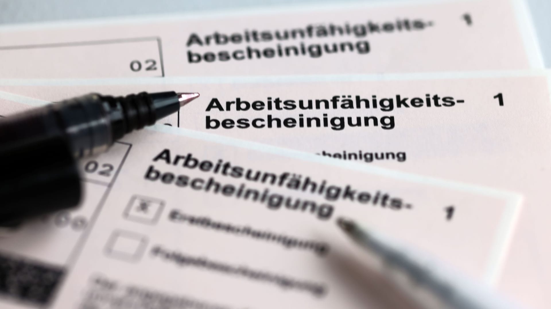 Stifte liegen auf Arbeitsunfähigkeitsbescheinigungen Stifte liegen auf Arbeitsunfähigkeitsbescheinigungen