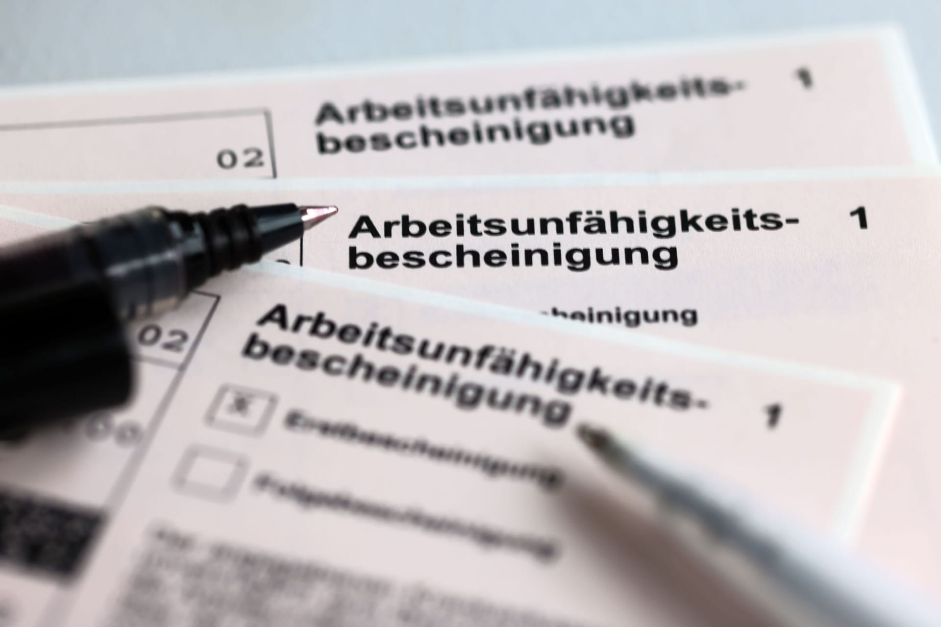 Stifte liegen auf Arbeitsunfähigkeitsbescheinigungen Stifte liegen auf Arbeitsunfähigkeitsbescheinigungen