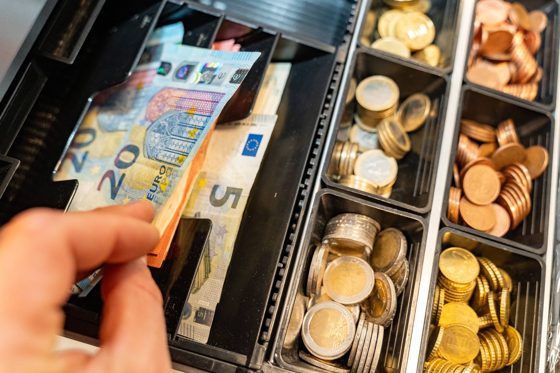 Ein Kassierer nimmt Geld aus der Kasse: Bald wird das Geldabheben an bestimmten Tankstellen nicht mehr möglich sein.
