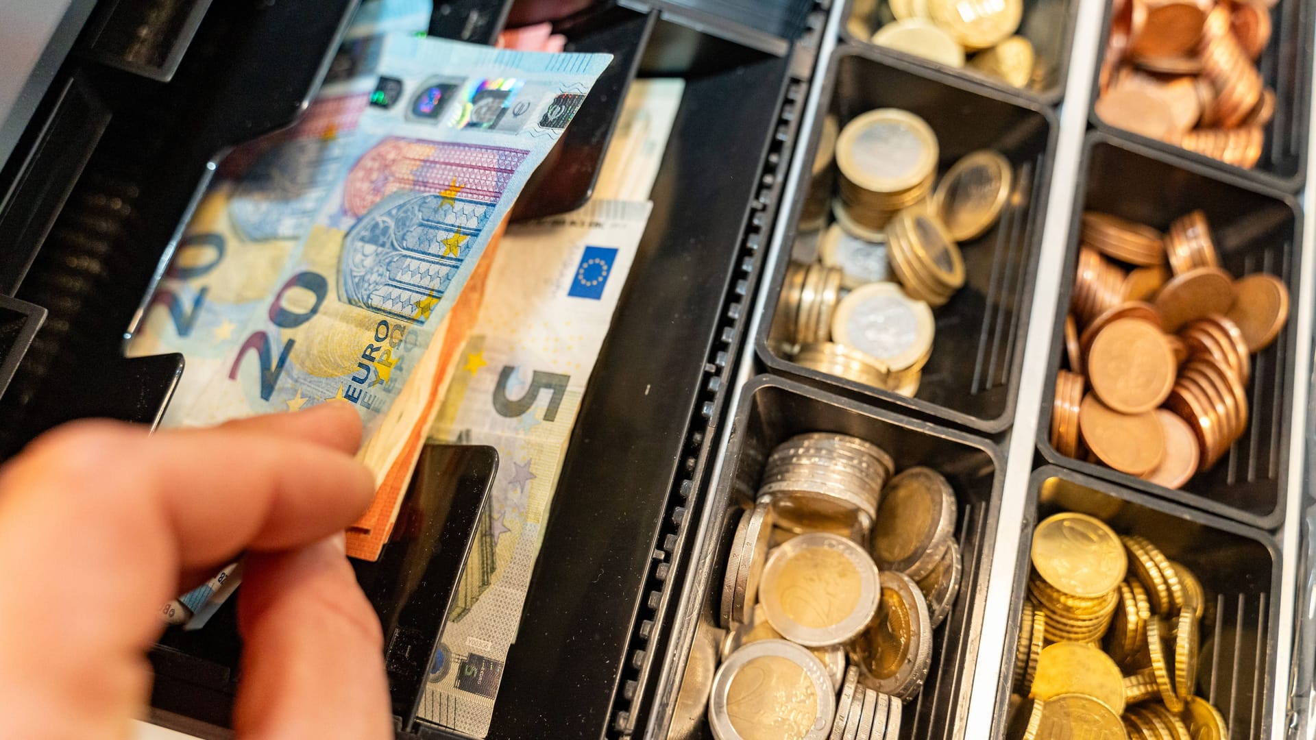 Ein Kassierer nimmt Geld aus der Kasse: Bald wird das Geldabheben an bestimmten Tankstellen nicht mehr möglich sein.