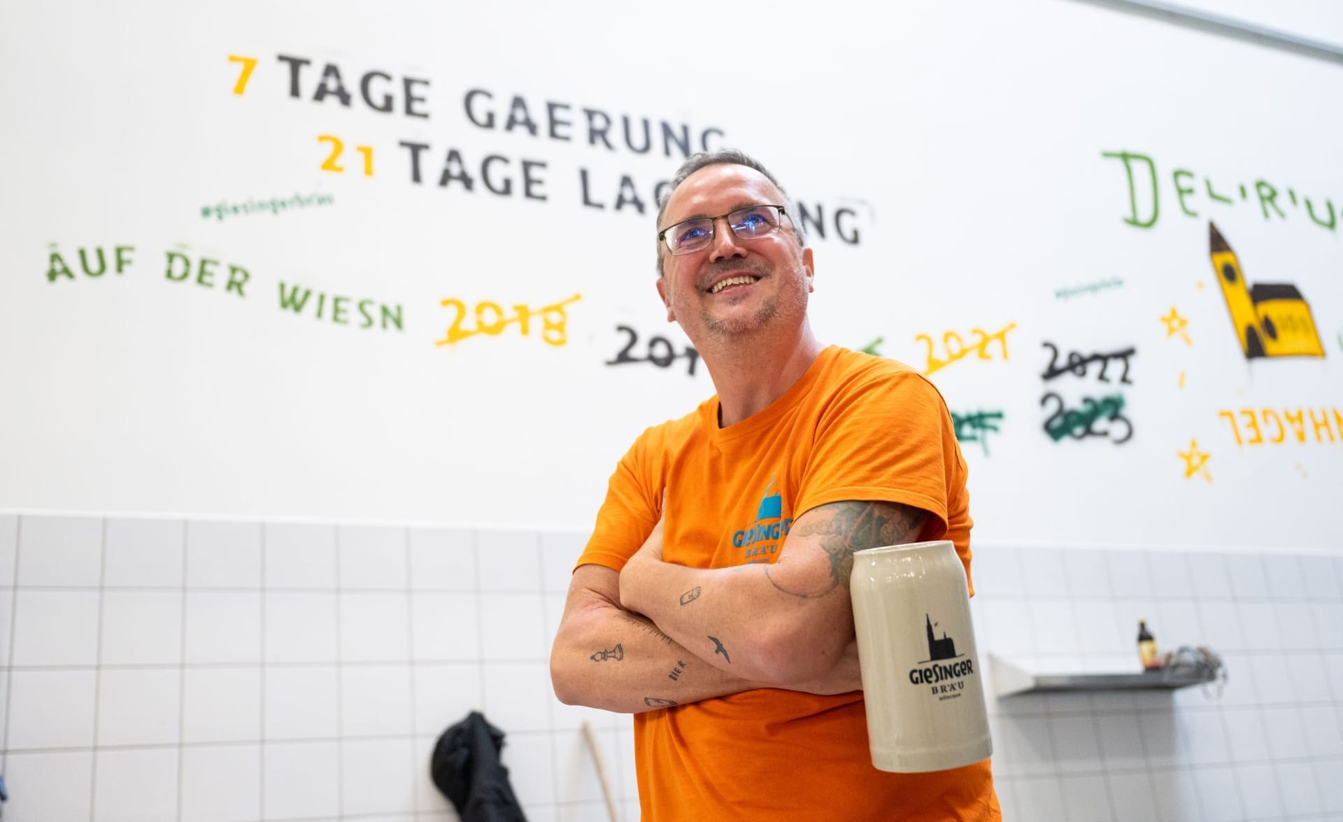 Der Gründer und Geschäftsführer der Giesinger Biermanufaktur, Steffen Marx, steht vor einer Wand in der Brauerei, auf der die Jahre durchgestrichen sind, in welchen die Brauerei nicht auf dem Oktoberfest vertreten war. (Archivfoto)